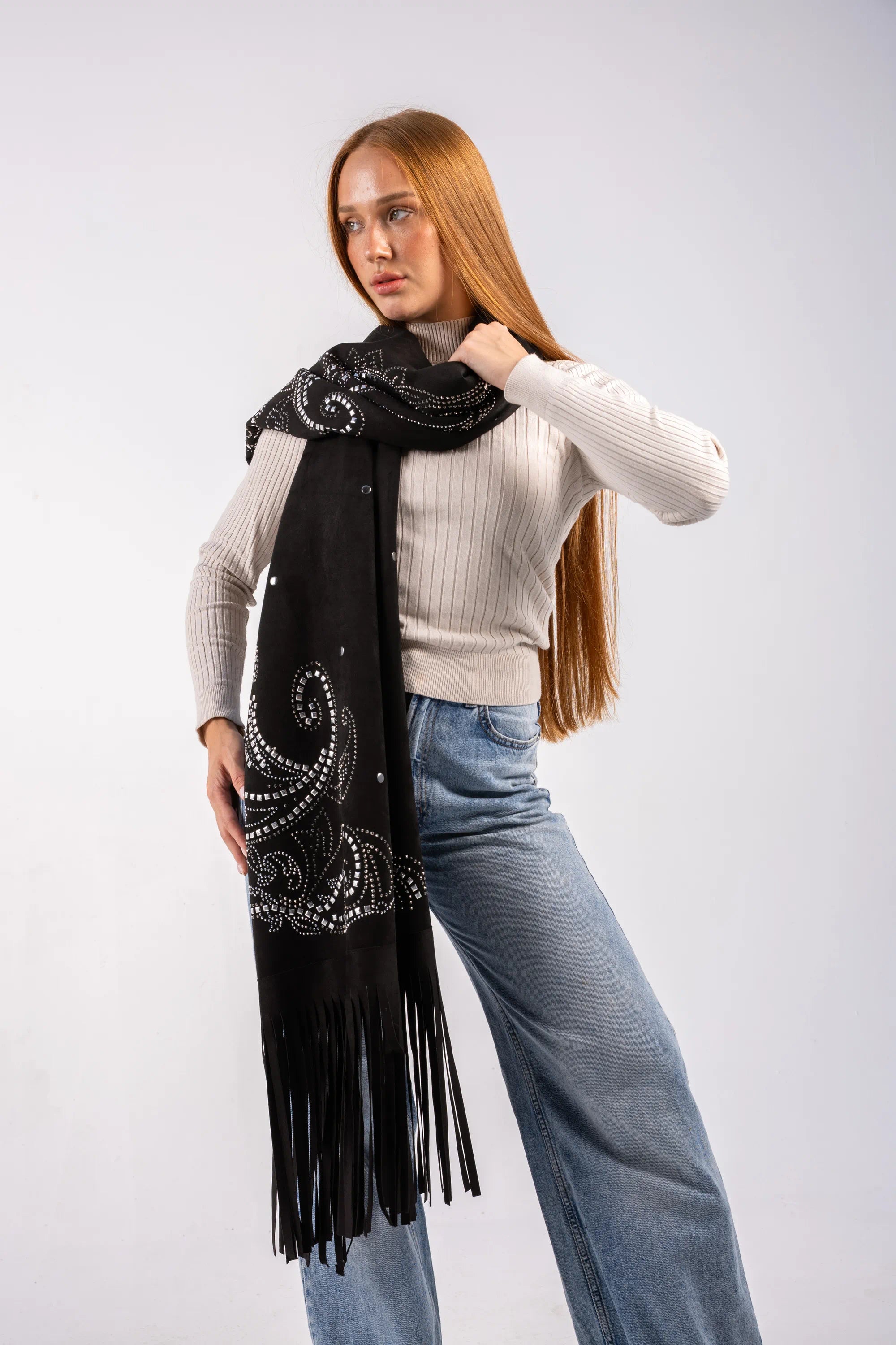 Woman wearing a black scarf with patterns and fringes on a white background