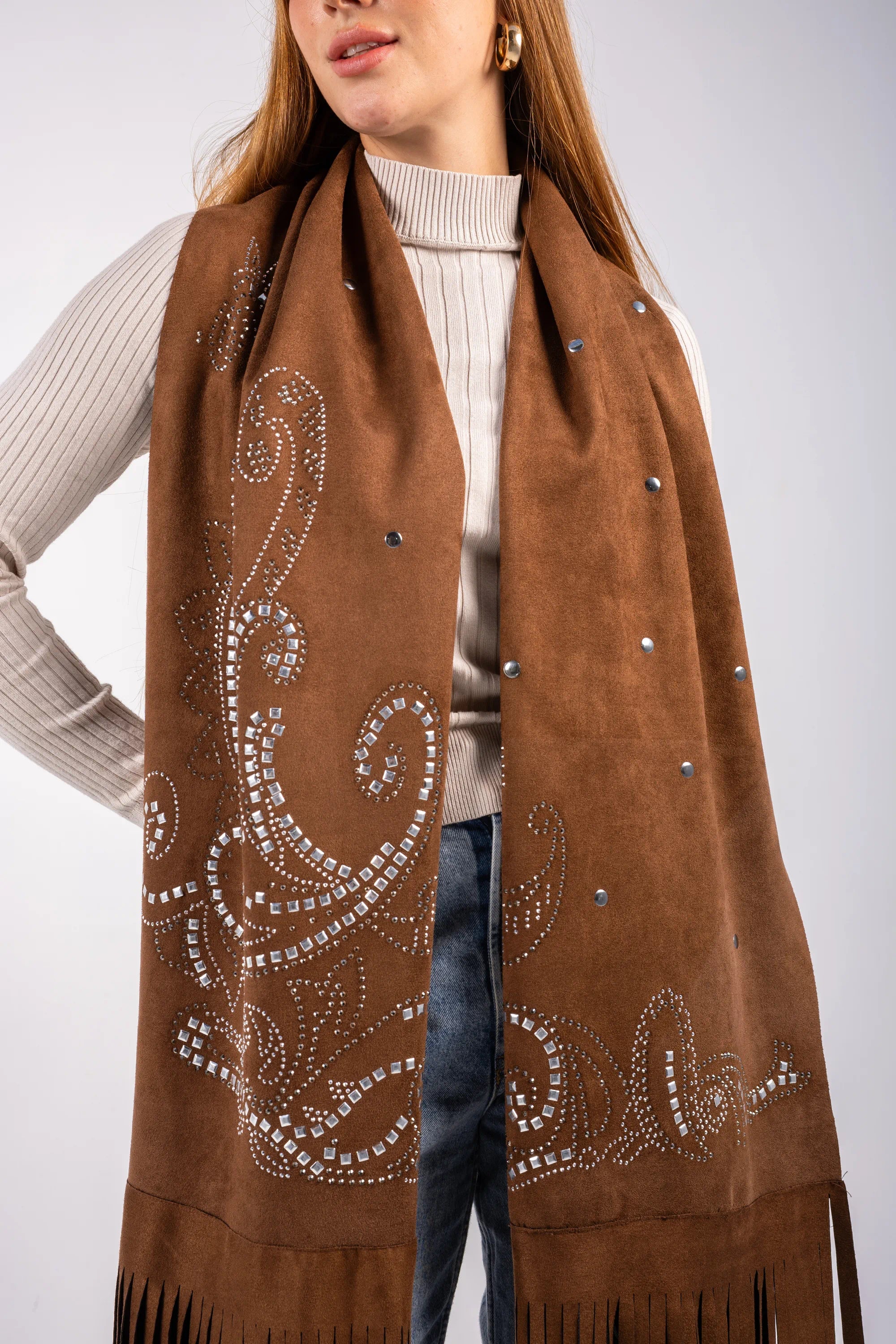 Brown scarf with decorative patterns and fringes worn by a person on a white background