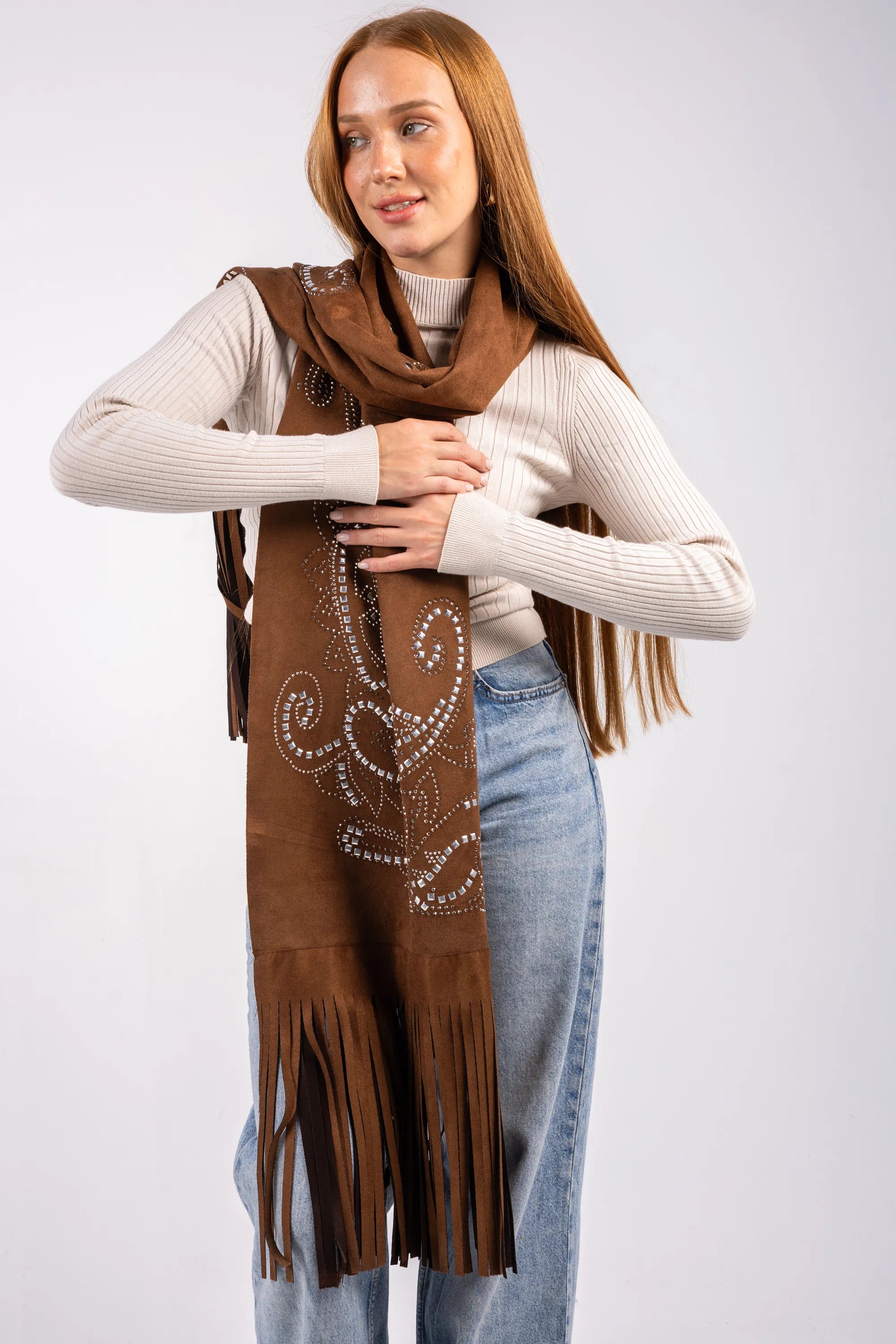 Woman wearing a brown suede scarf with decorative patterns and fringes on a white background