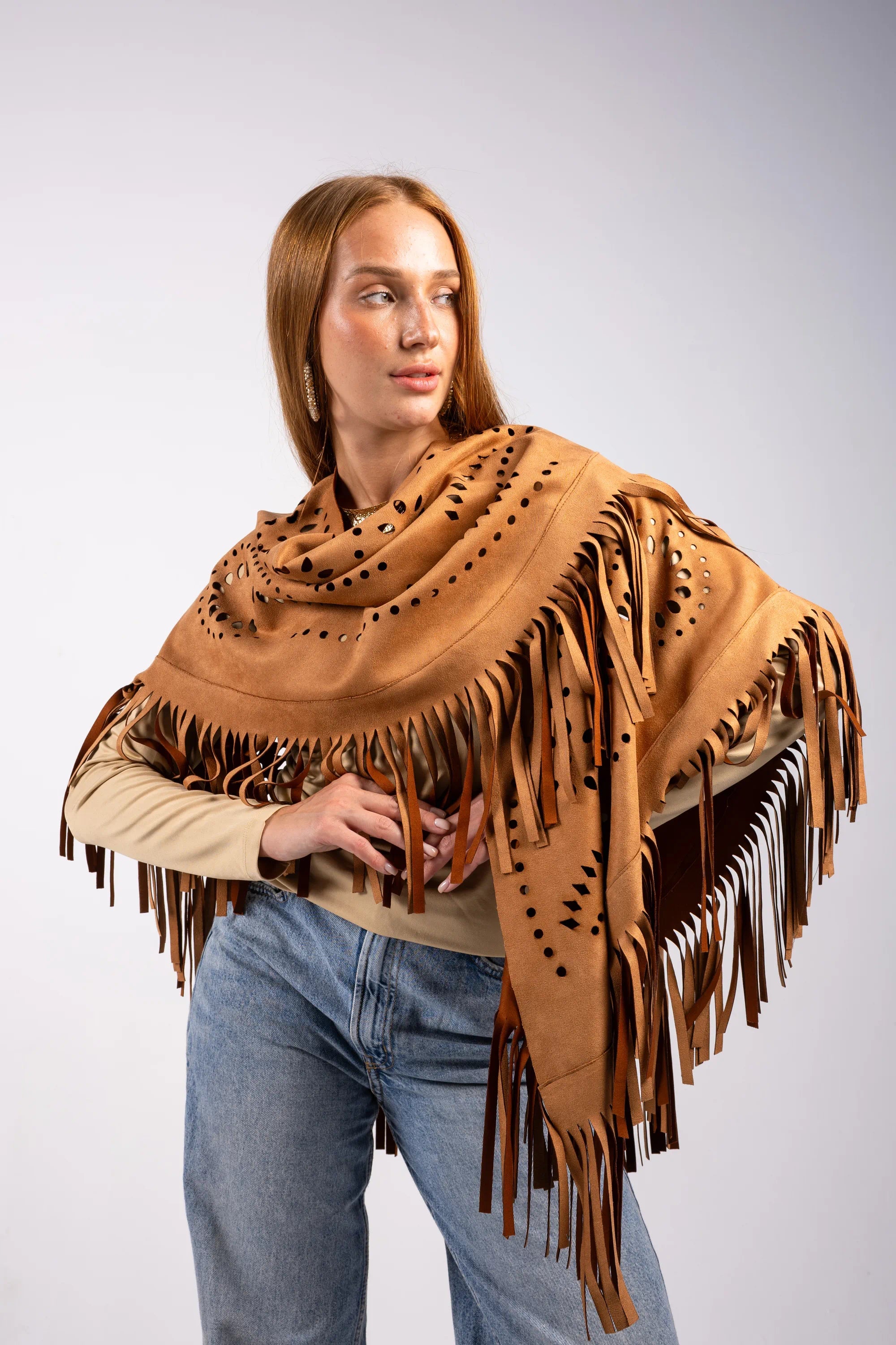 Woman wearing a brown leather fringe shawl on a plain background