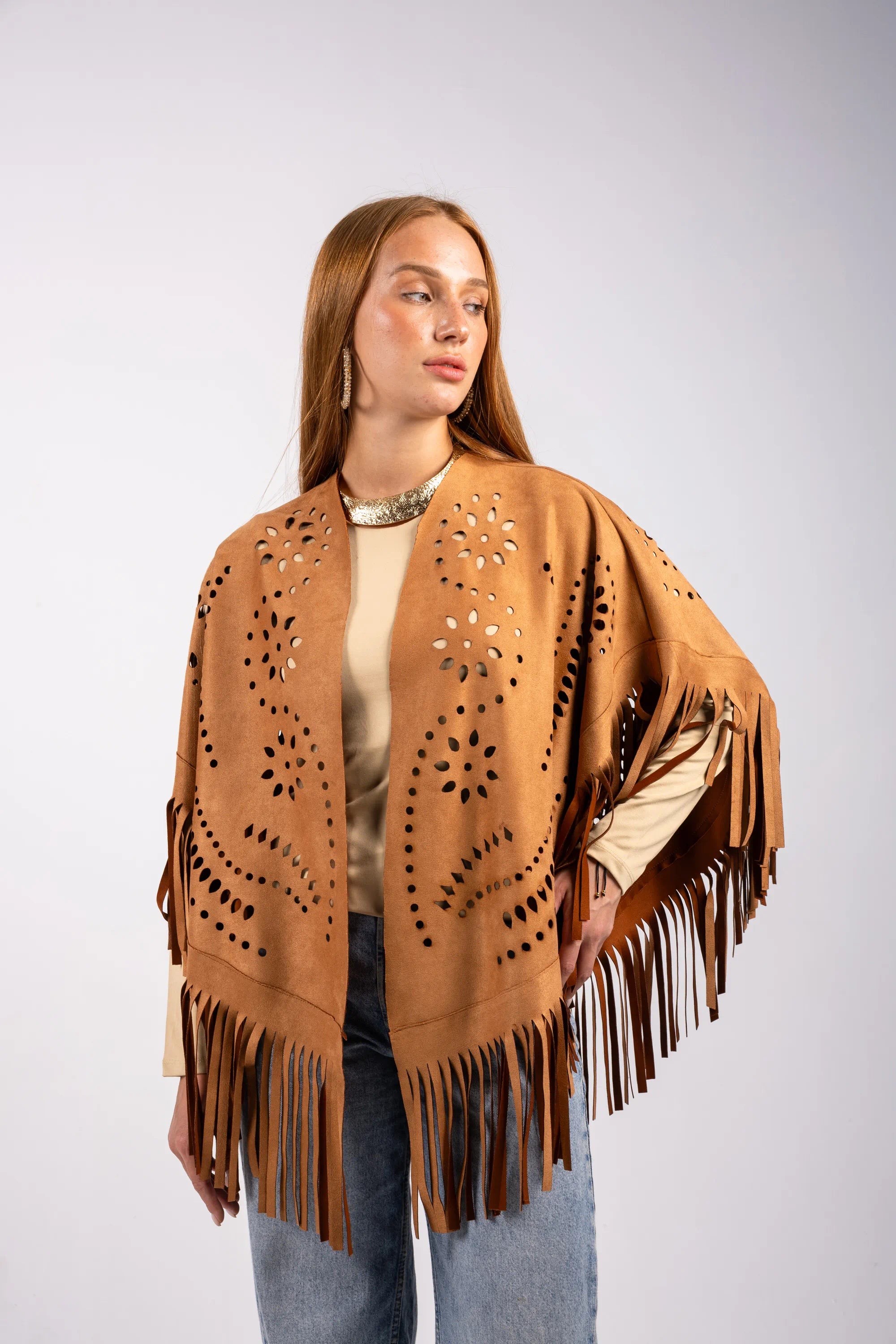 Woman wearing a brown fringe poncho on a light gray background
