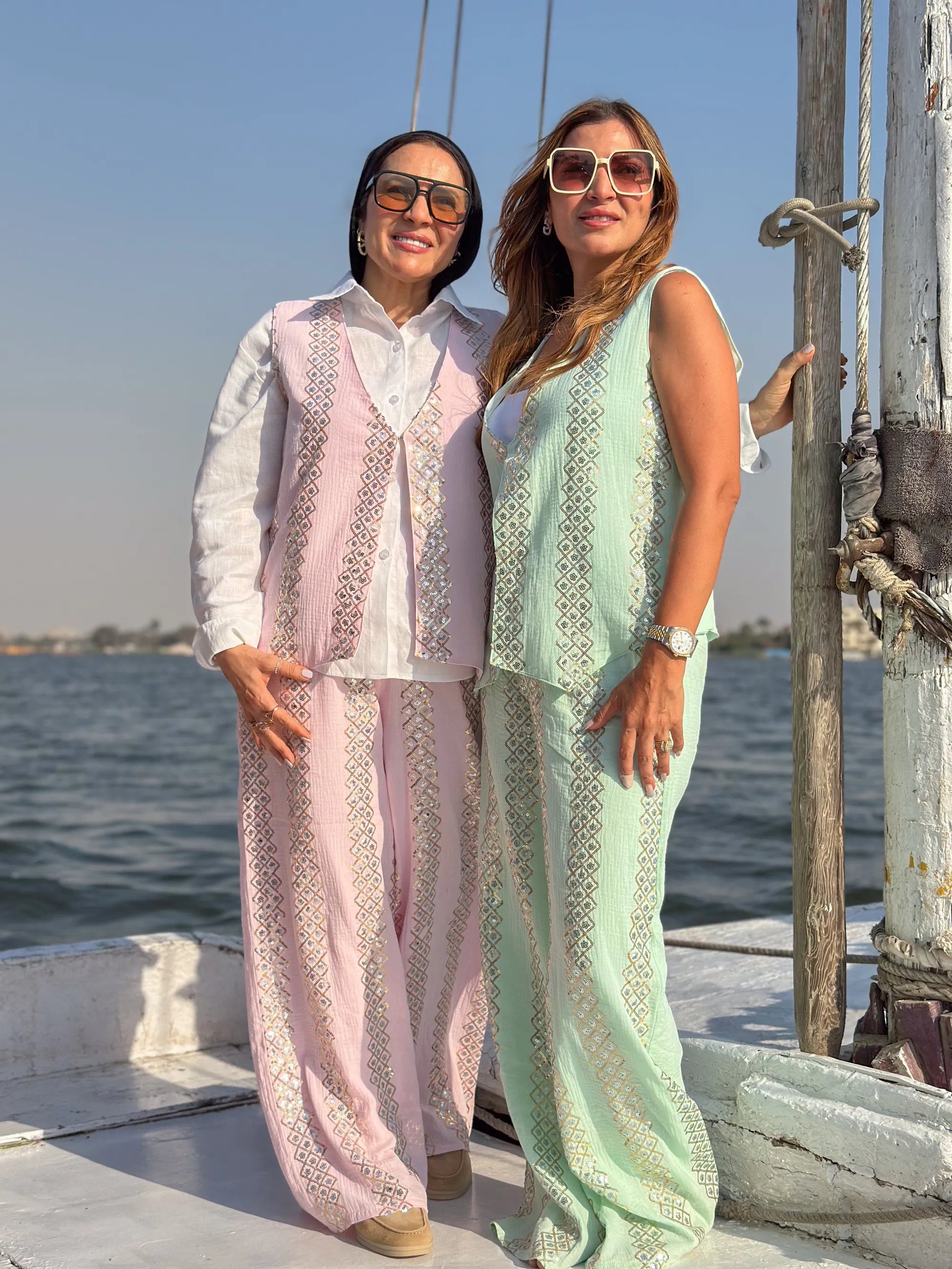 Two women standing on a boat with water and sky in the background
