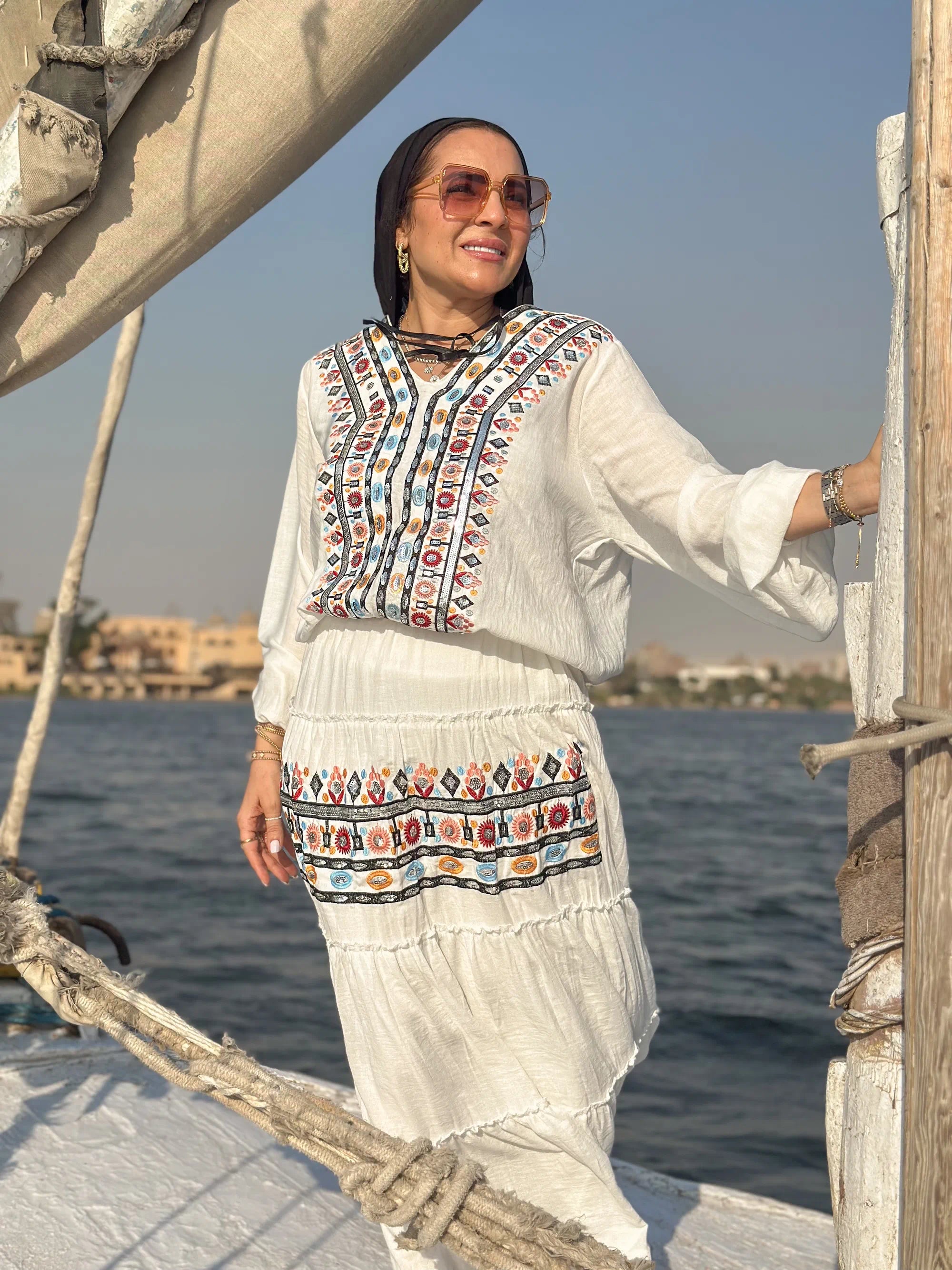 Woman in traditional outfit on a boat with water and sky in the background