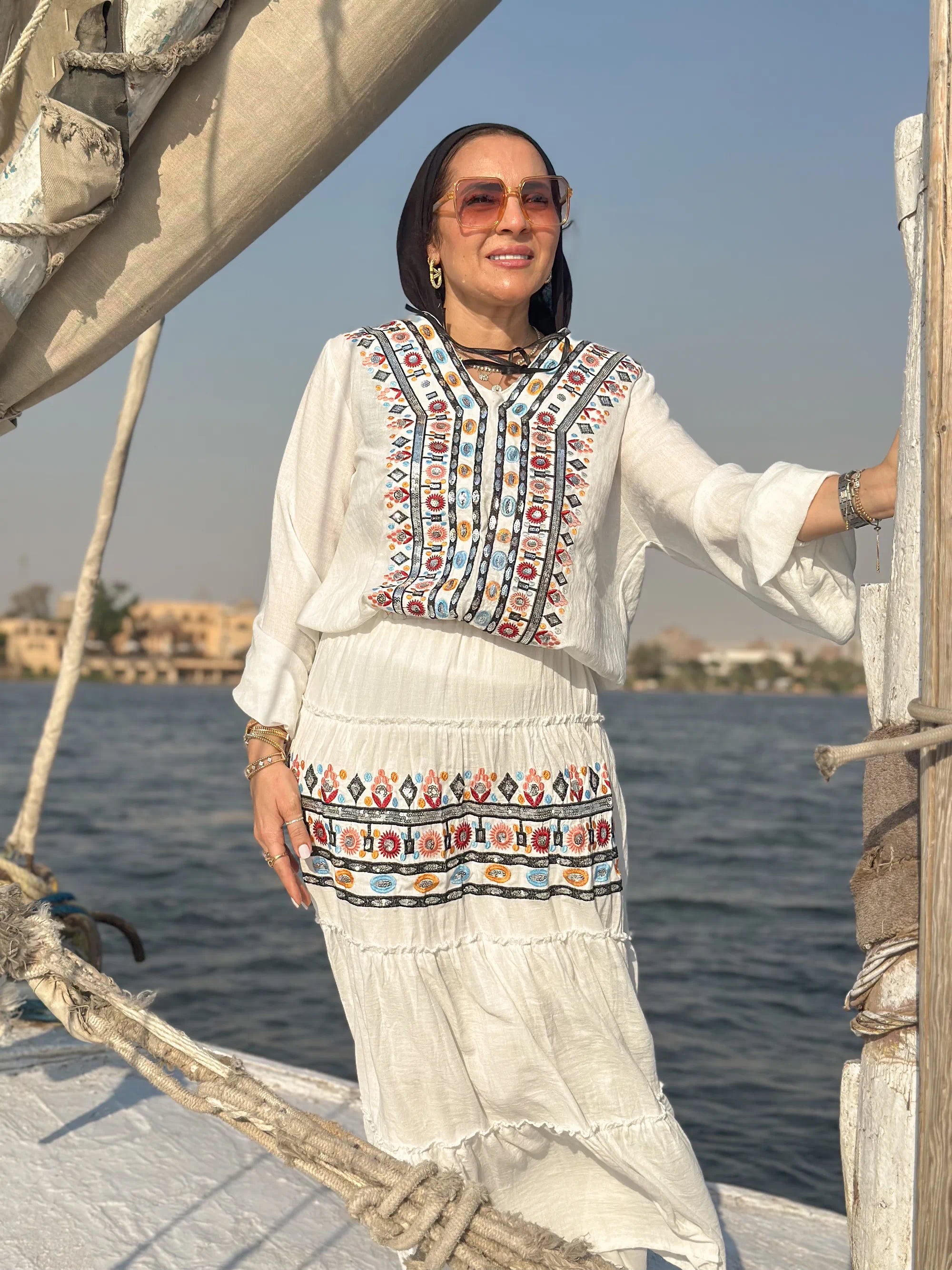 Woman in traditional outfit on a boat with water and skyline in the background