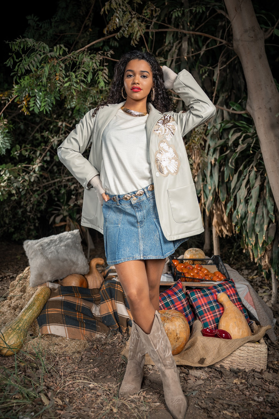 Woman in a casual outfit with a plaid blanket and pumpkins in a natural setting