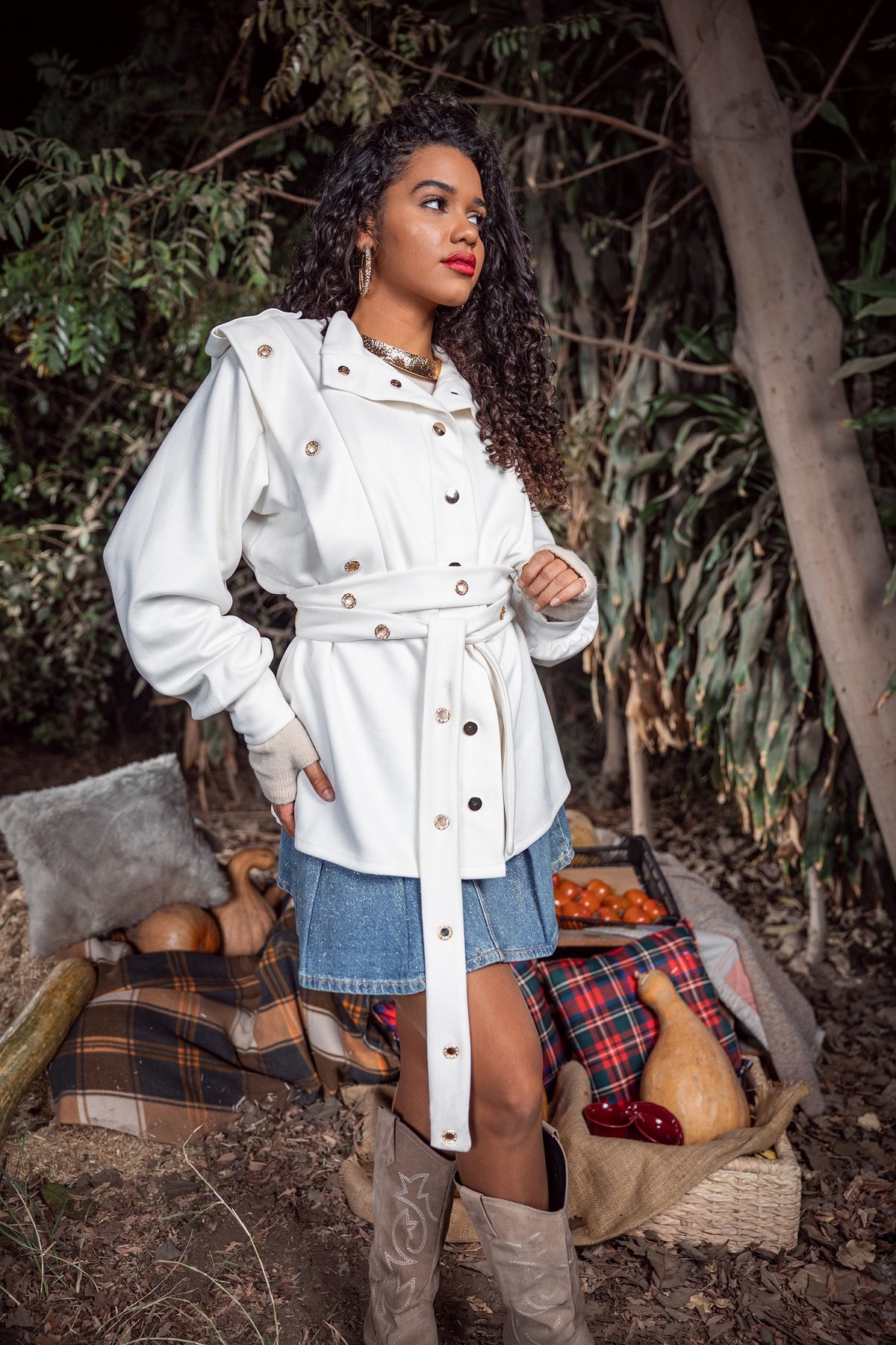 Woman in a white coat standing outdoors with a rustic background