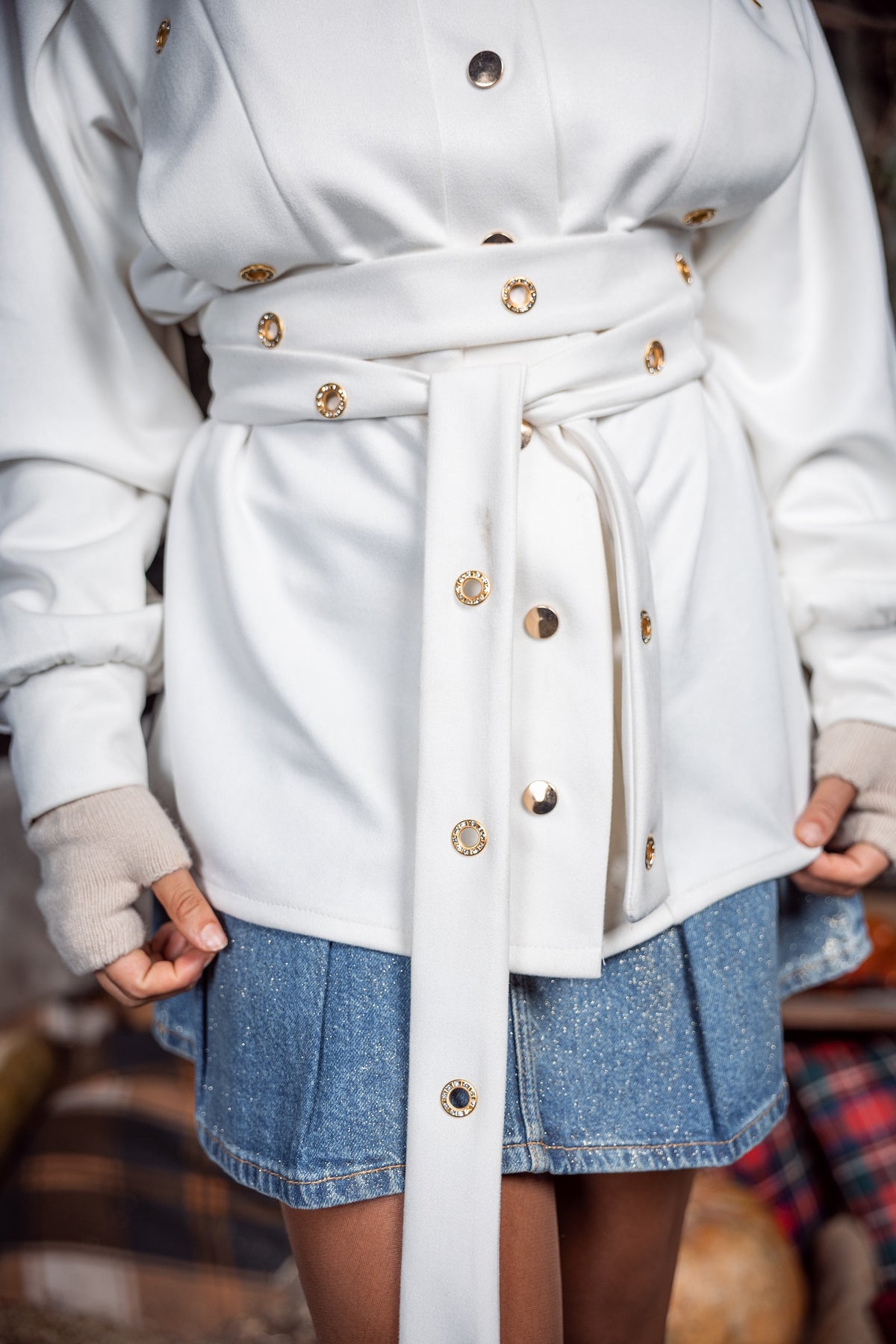 White coat with gold buttons worn by a person, with a blurred background