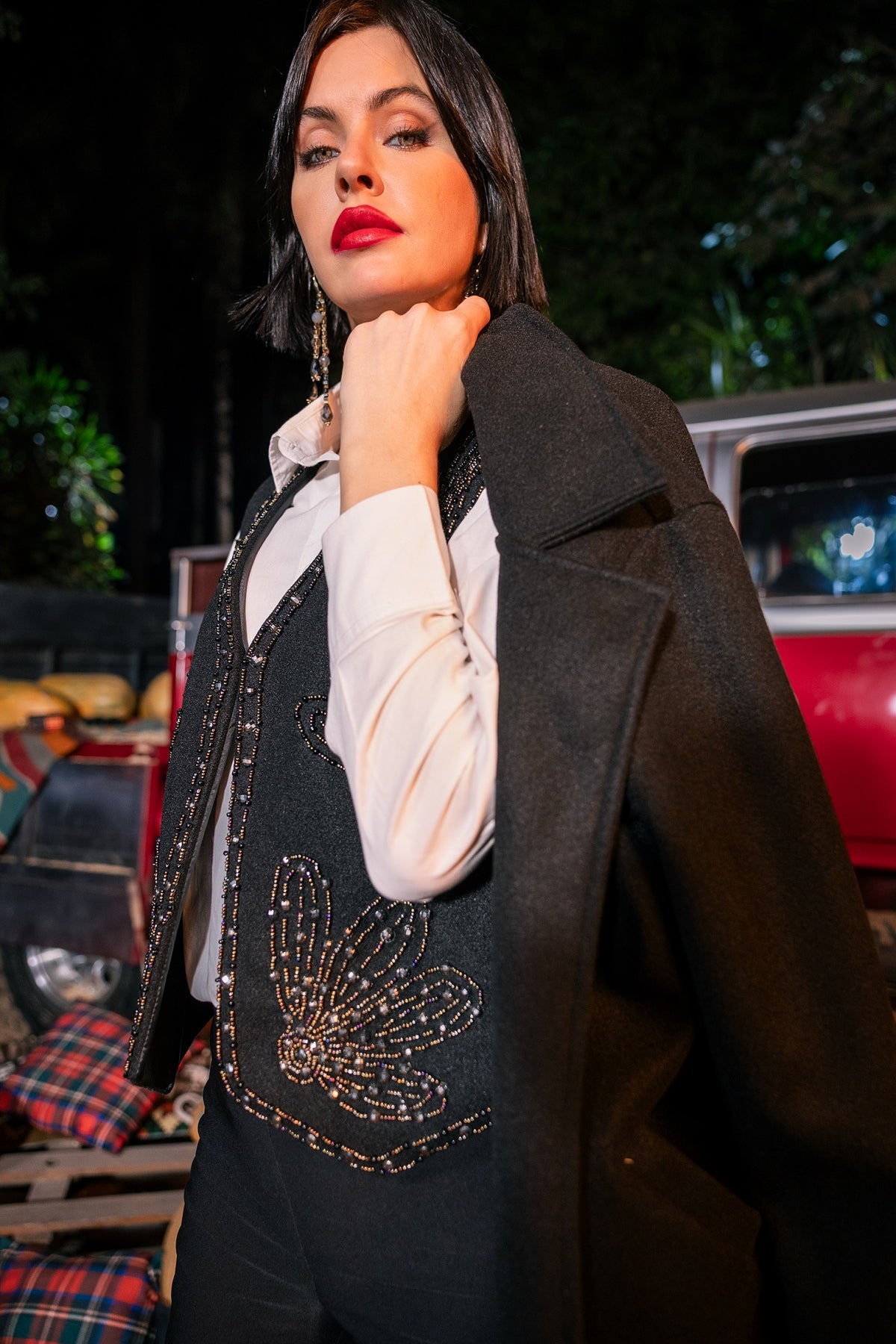 Woman wearing a dark coat with a decorative vest in an outdoor setting