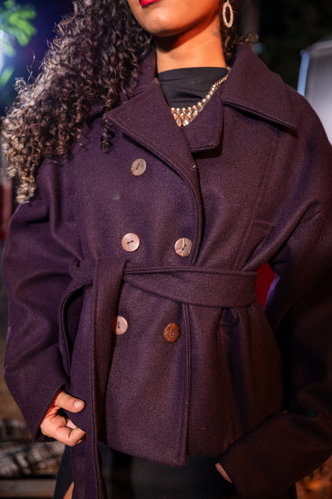 Person wearing a dark purple coat with button details