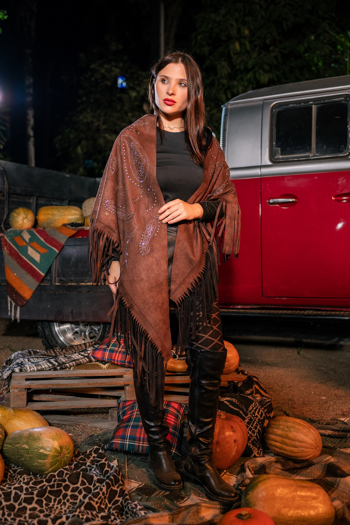 Woman standing in front of a vintage truck with pumpkins at night