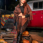 Woman in a brown fringed poncho standing in front of a red truck with pumpkins around.