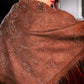 Brown shawl with paisley patterns and fringes worn by a person.