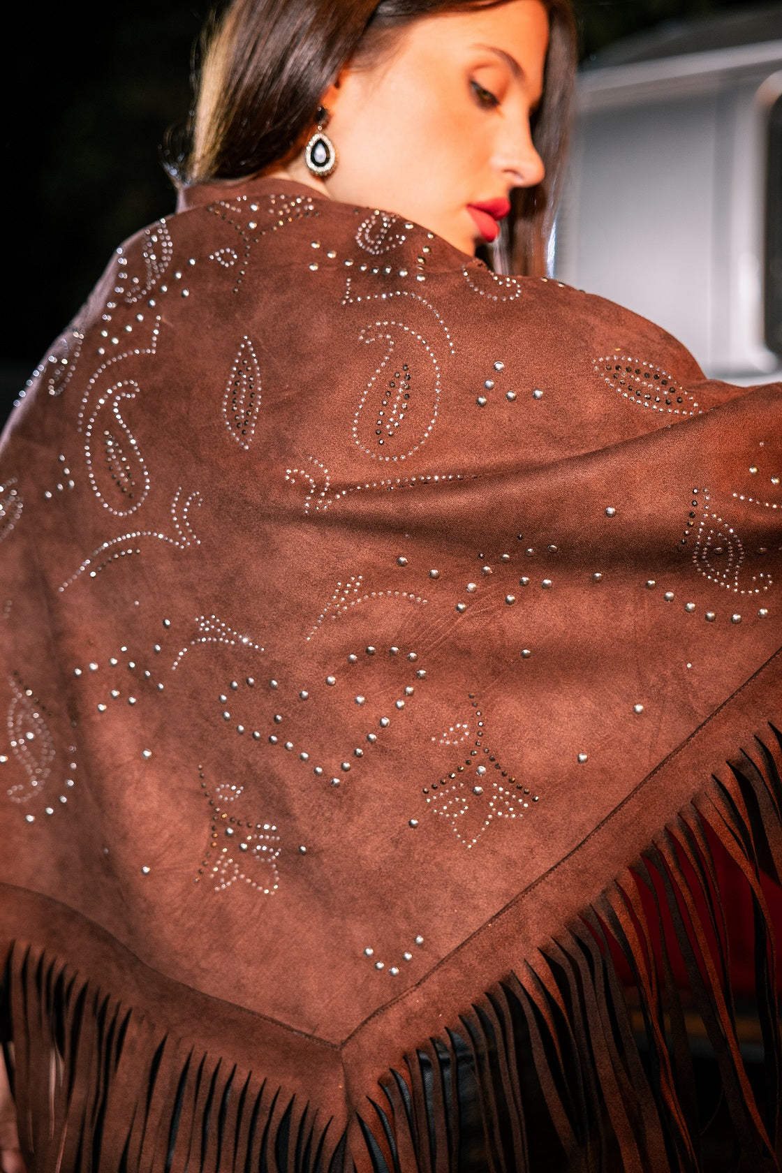 Brown shawl with paisley patterns and fringes worn by a person.