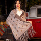Woman wearing a star-patterned shawl in front of a vintage red truck.
