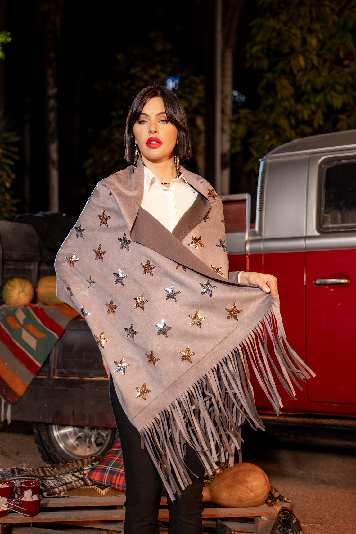 Woman wearing a star-patterned shawl in front of a vintage red truck.