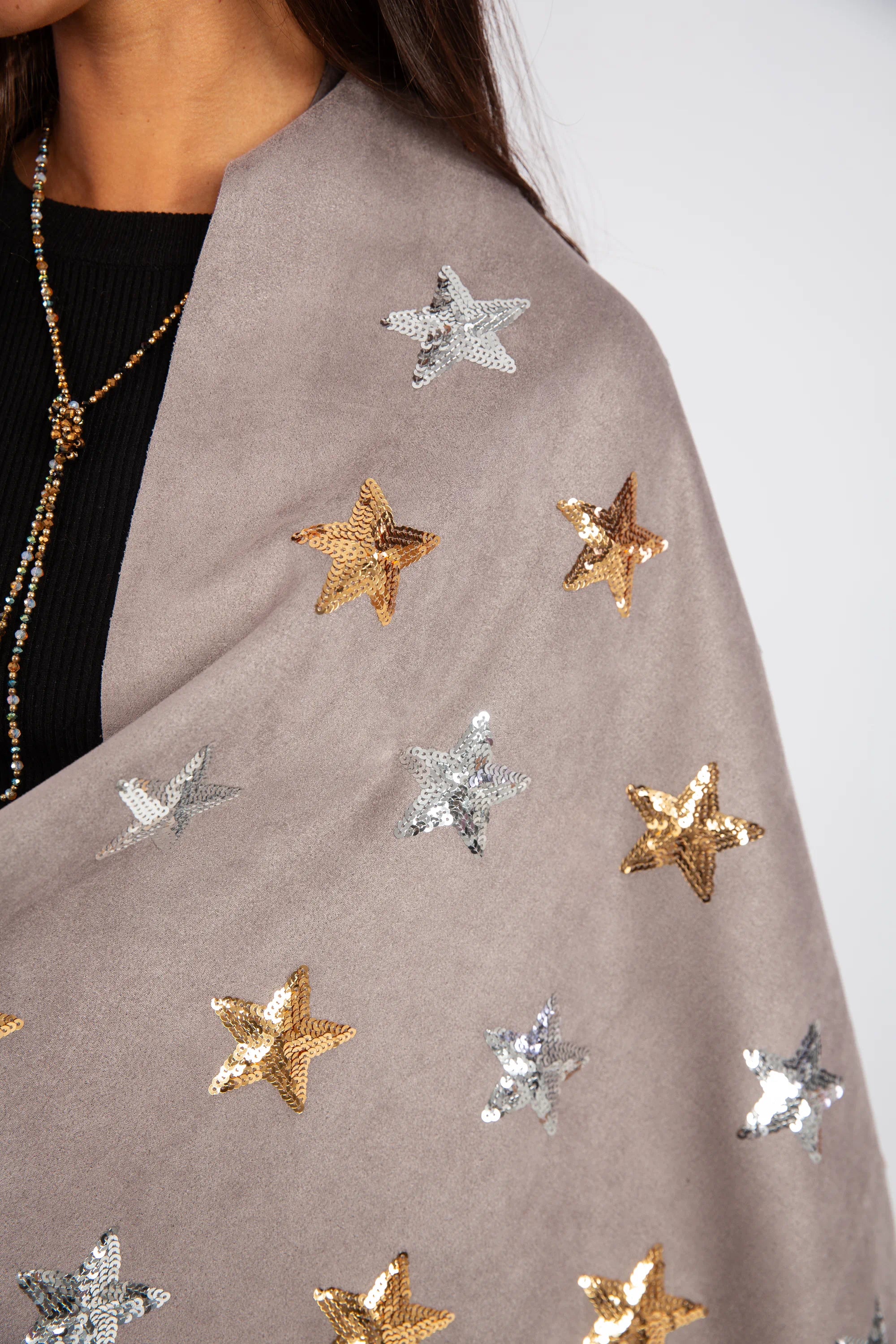 Gray scarf with gold and silver star patterns worn by a person.