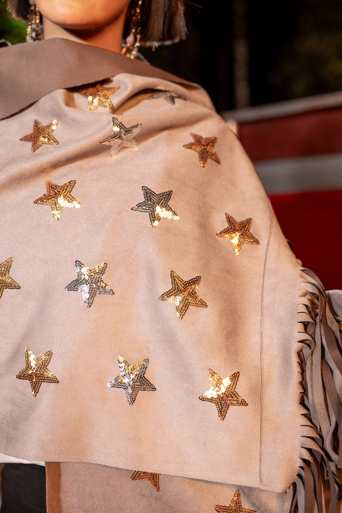 Close-up of a beige coat with star-shaped embellishments on a blurred background