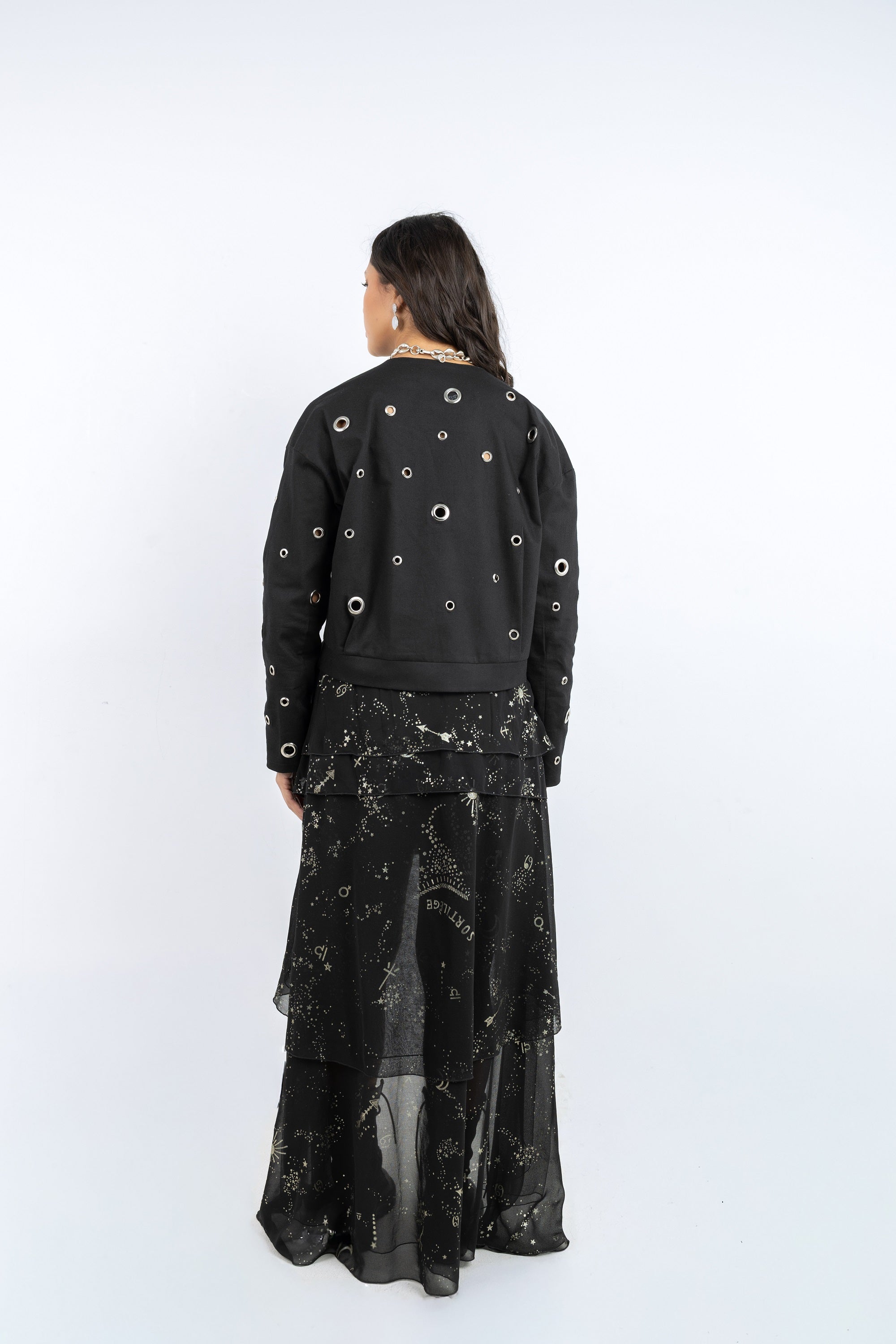 Person wearing a black outfit with circular patterns on a white background