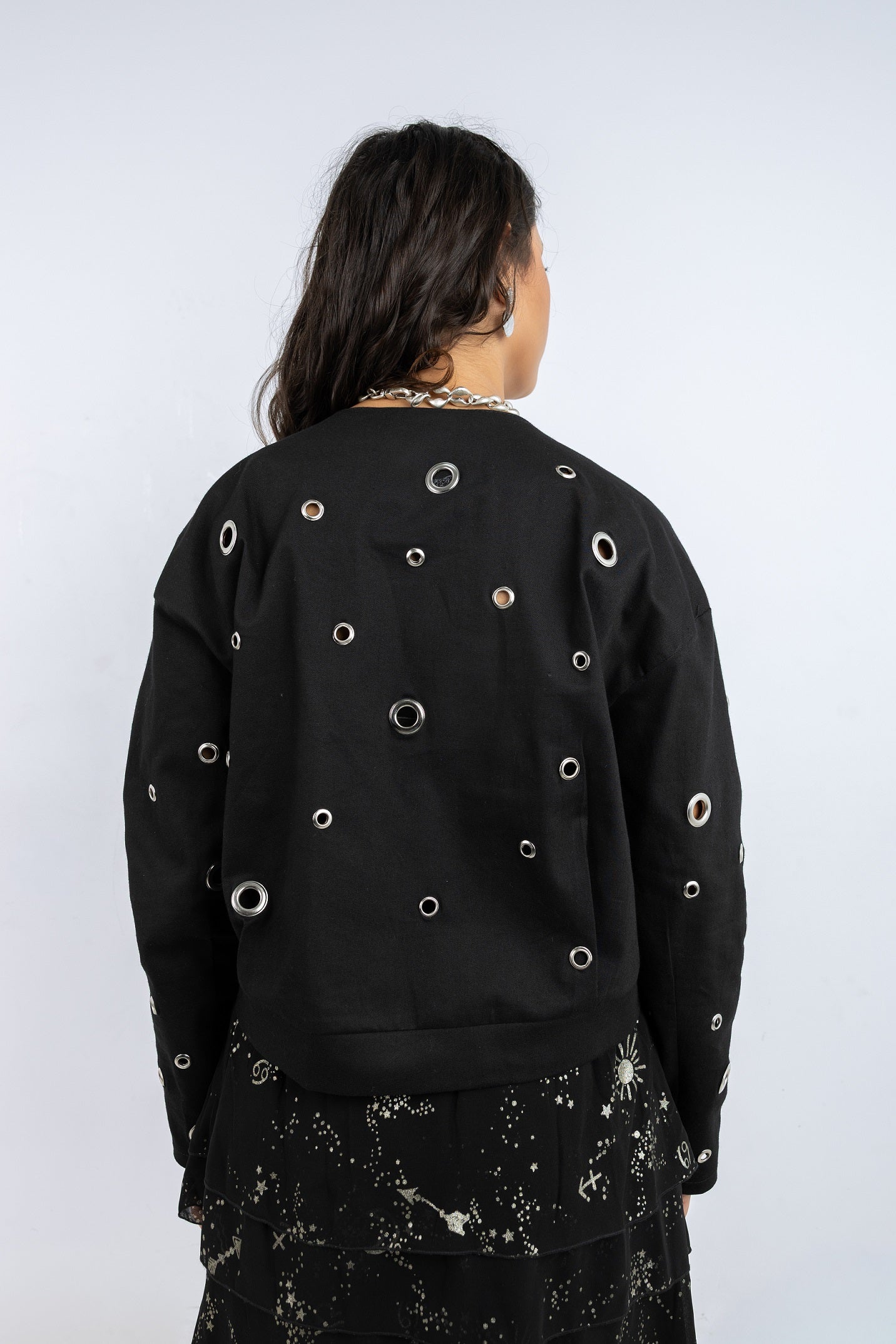 Person wearing a black sweatshirt with circular cutouts on a white background