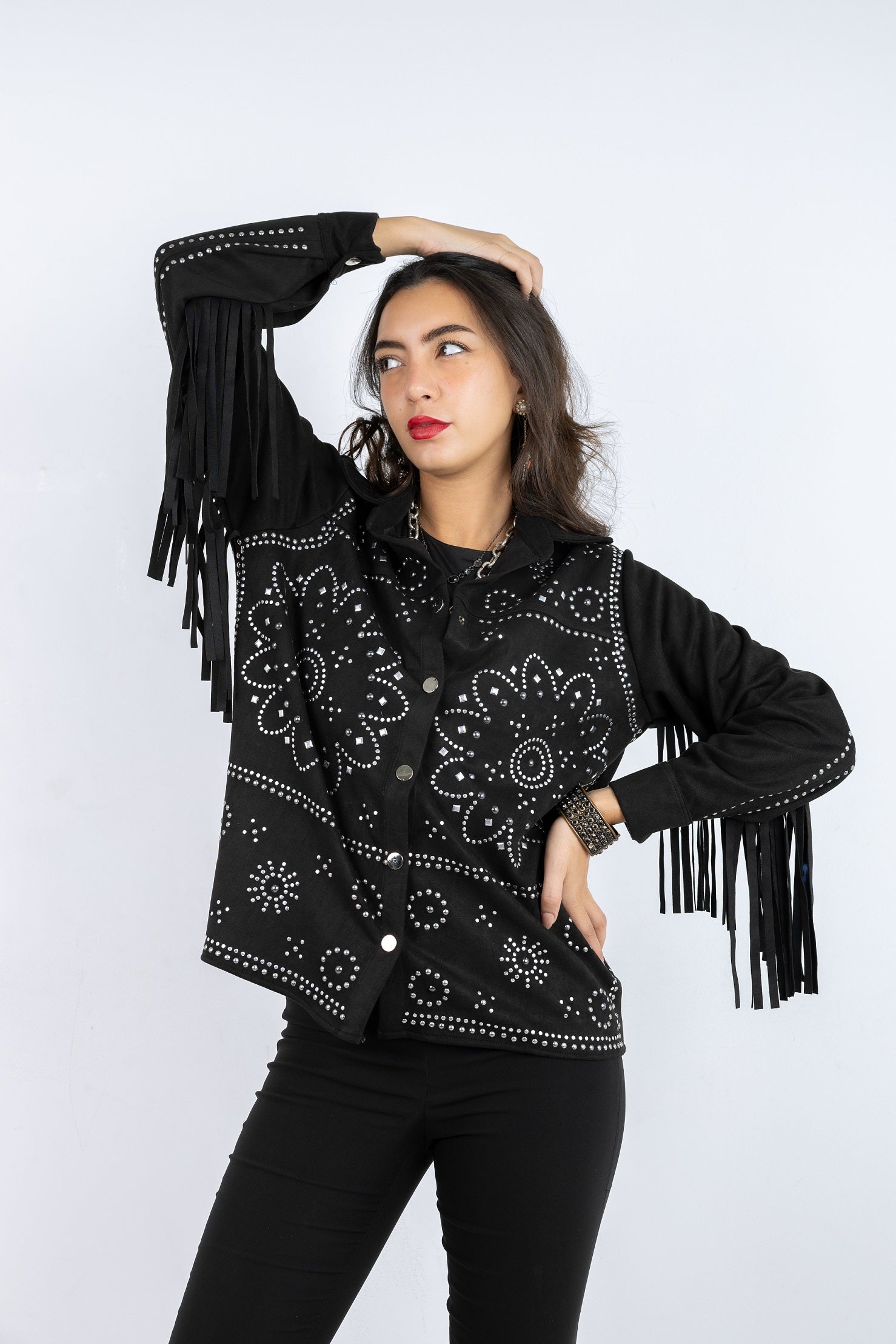 Woman wearing a black embroidered jacket with fringe on a white background