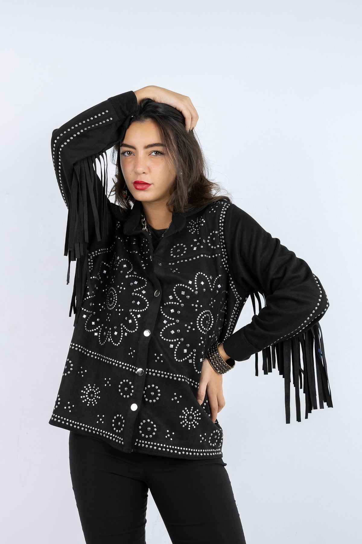 Woman wearing a black jacket with fringe and patterned design on a white background