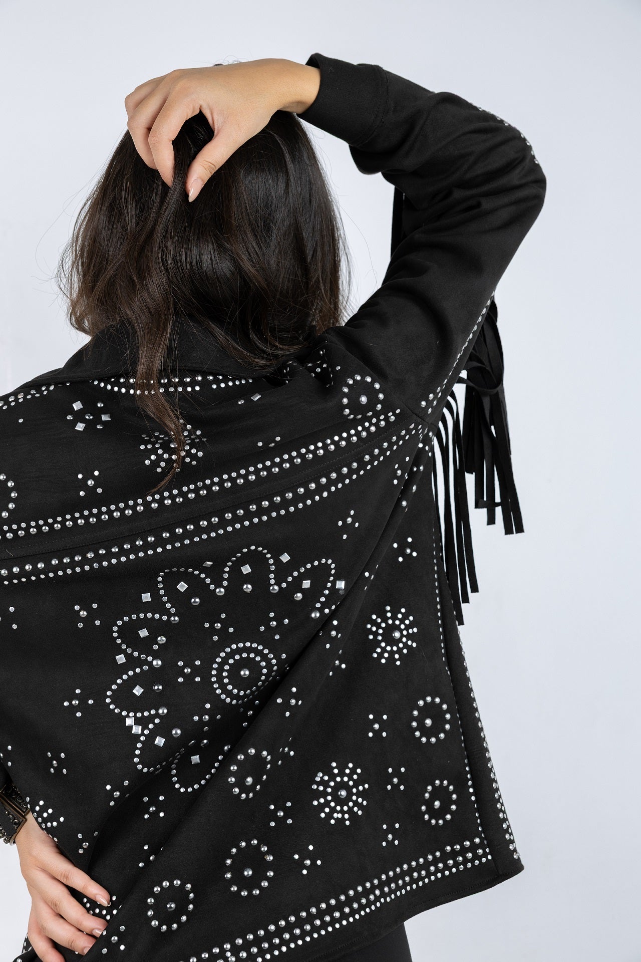 Black jacket with floral patterns and fringes on a plain background