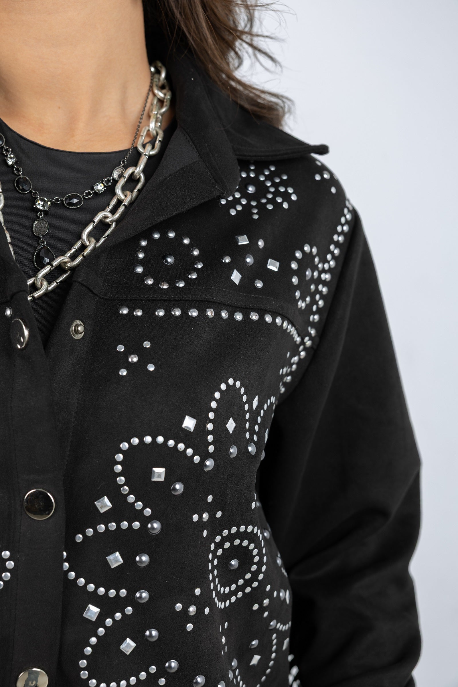 Black jacket with silver studded details on a plain background