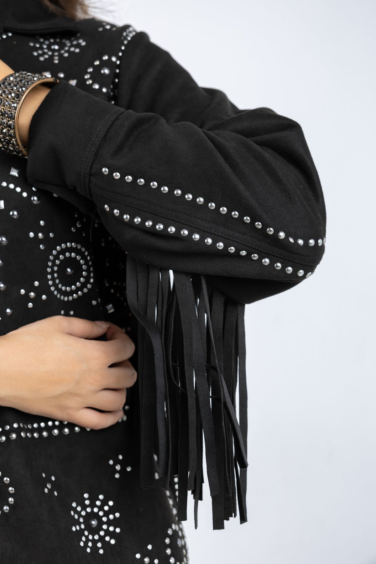 Black studded and fringed garment on a white background
