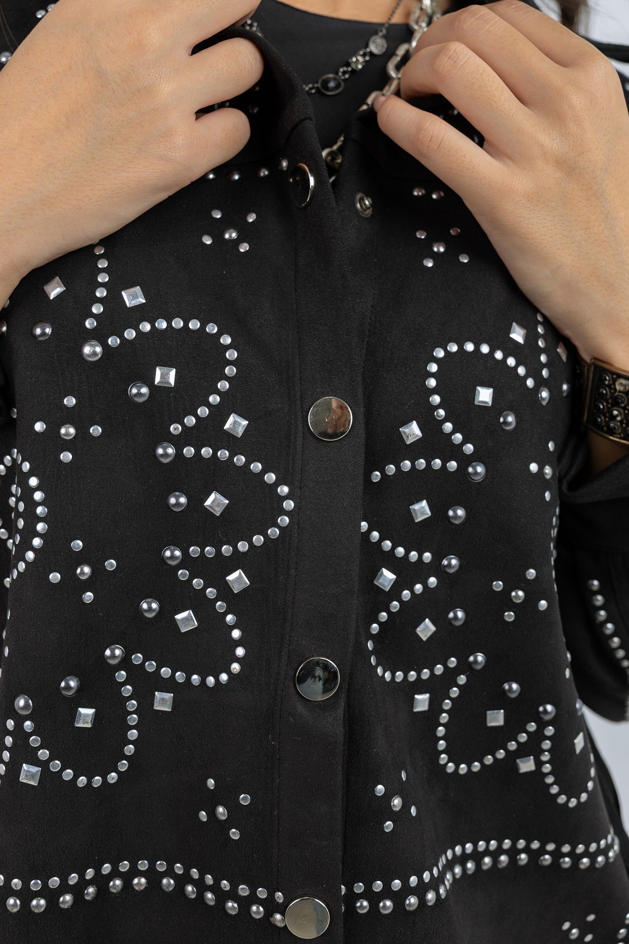 Black jacket with decorative studding being adjusted by hands