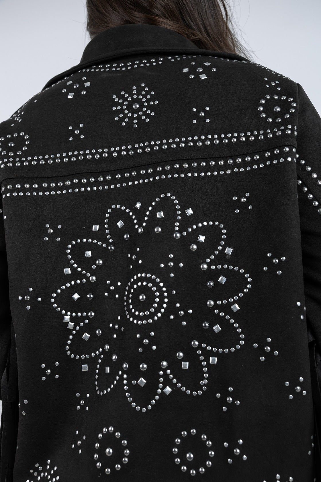 Black jacket with silver studded patterns on a plain background