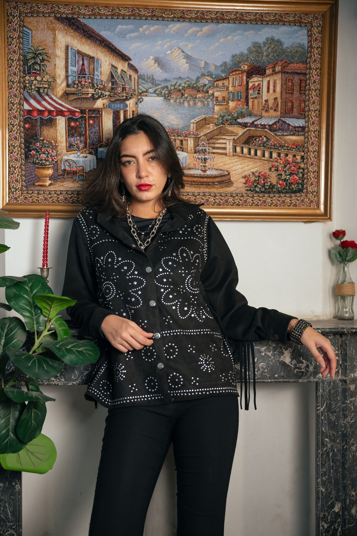 Woman posing indoors with a decorative tapestry in the background