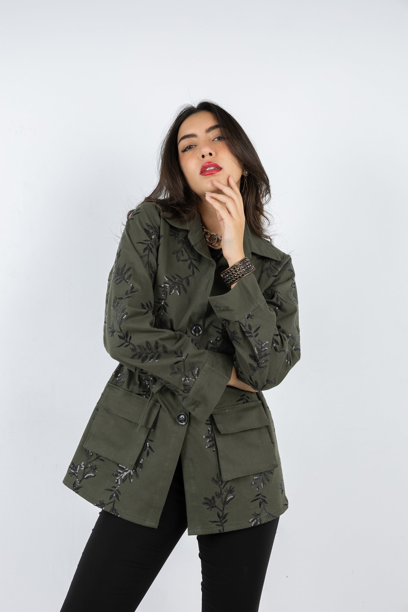 Woman wearing a green embroidered jacket on a white background