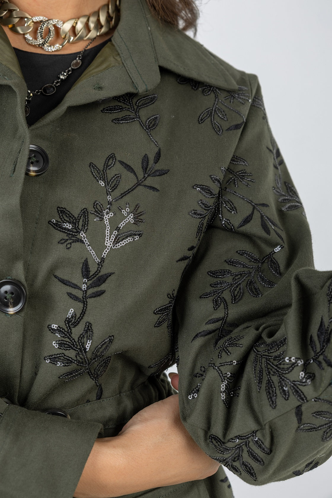 Green coat with black floral embroidery on a white background