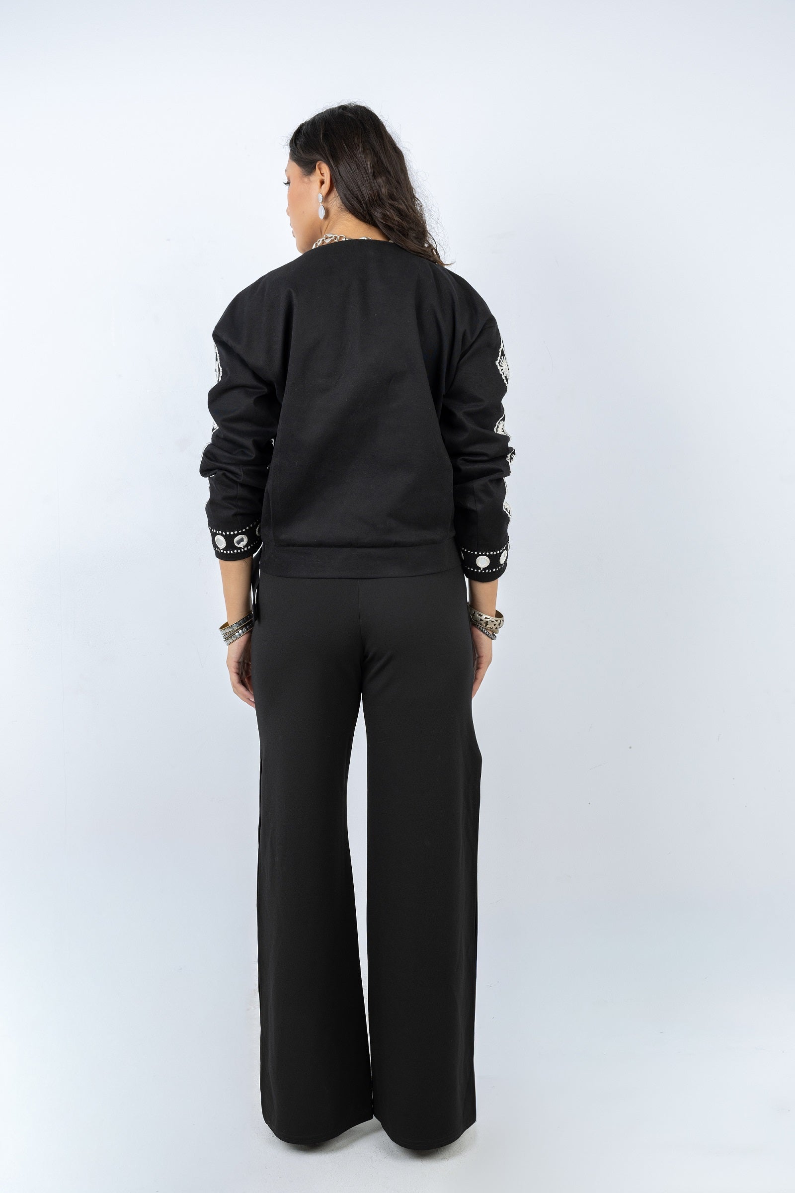 Person wearing a black outfit with wide-leg pants on a white background