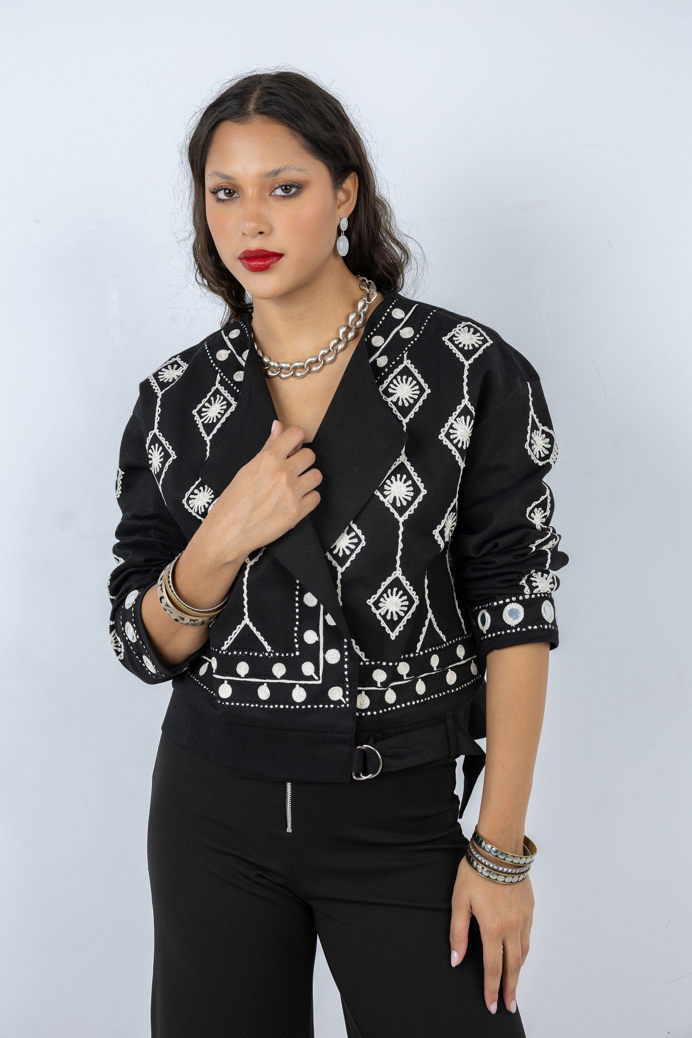 Woman wearing a black jacket with white patterns on a plain background