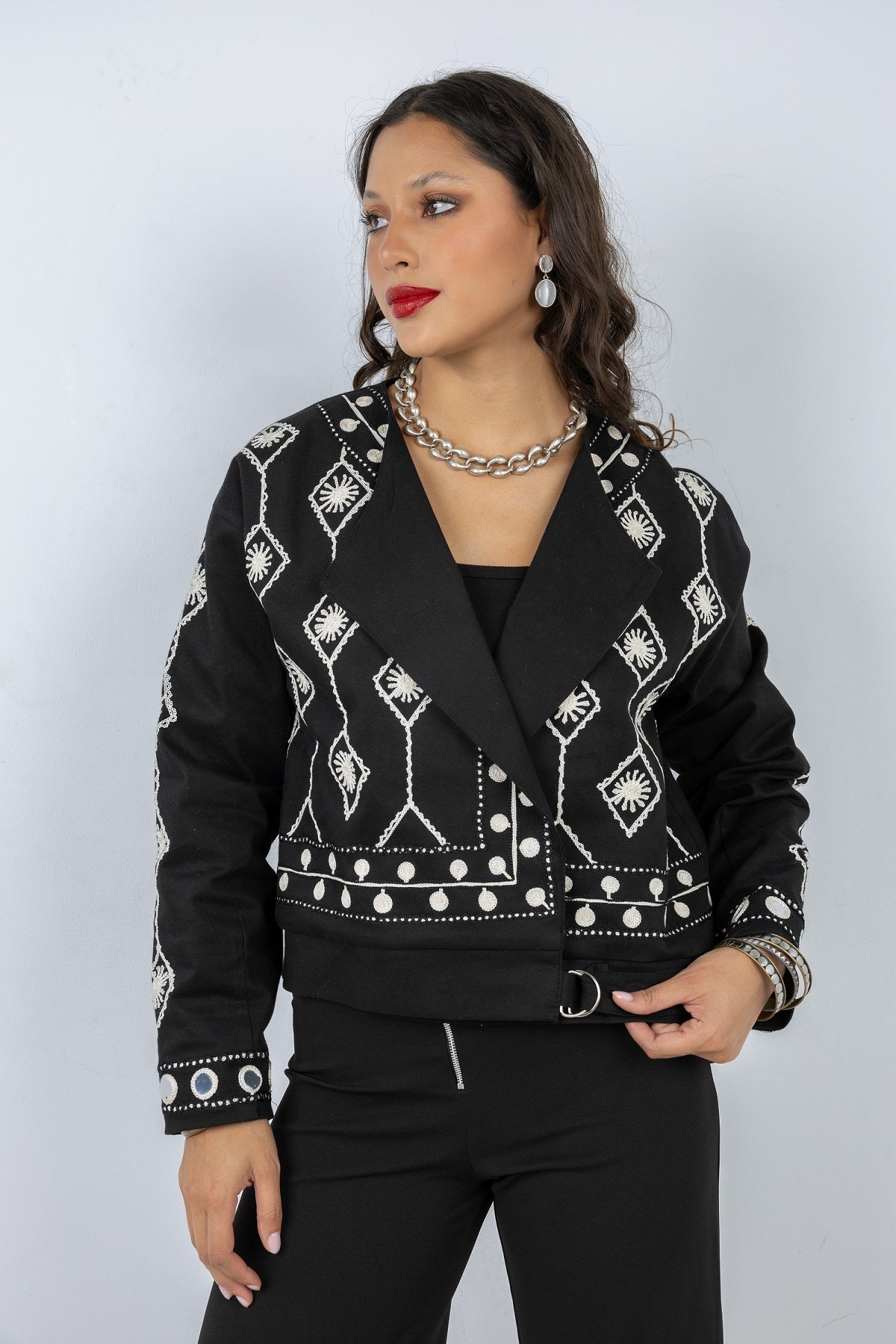 Woman wearing a black jacket with white patterns on a plain background