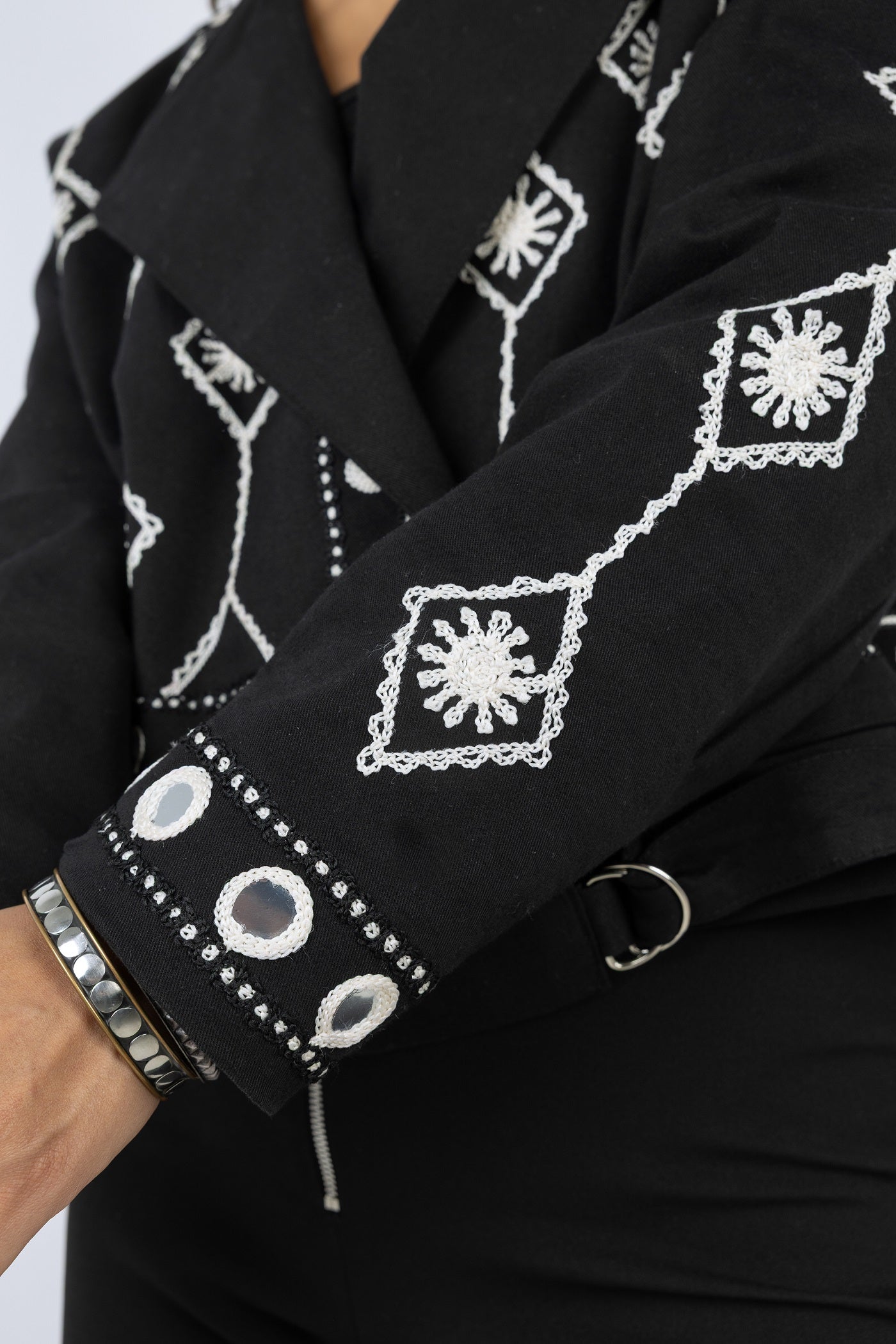 Black garment with white embroidery on a plain background