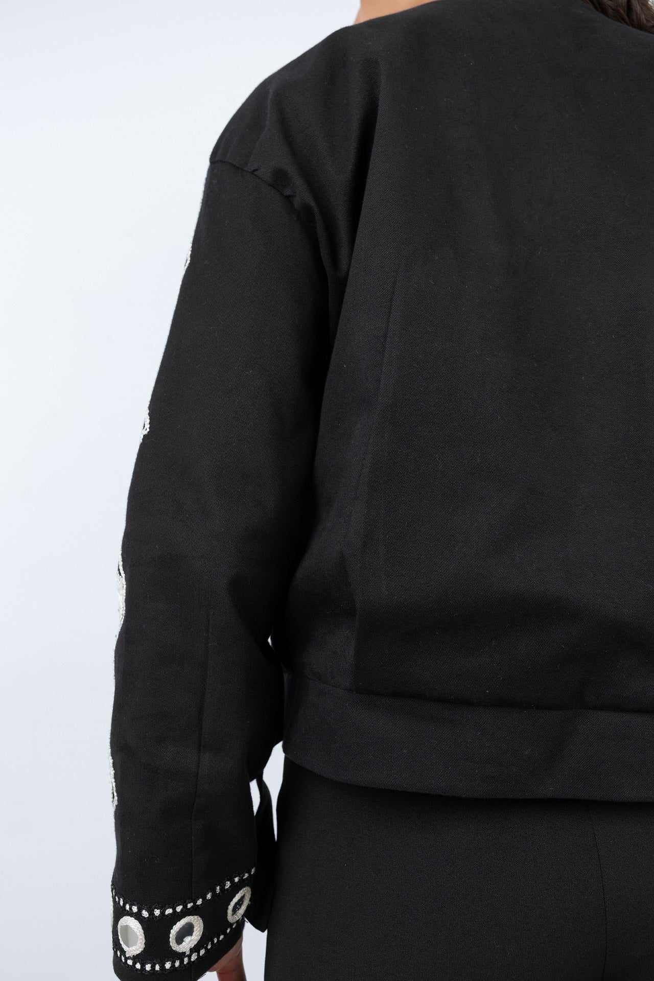 Black outfit with decorative cuffs on a white background