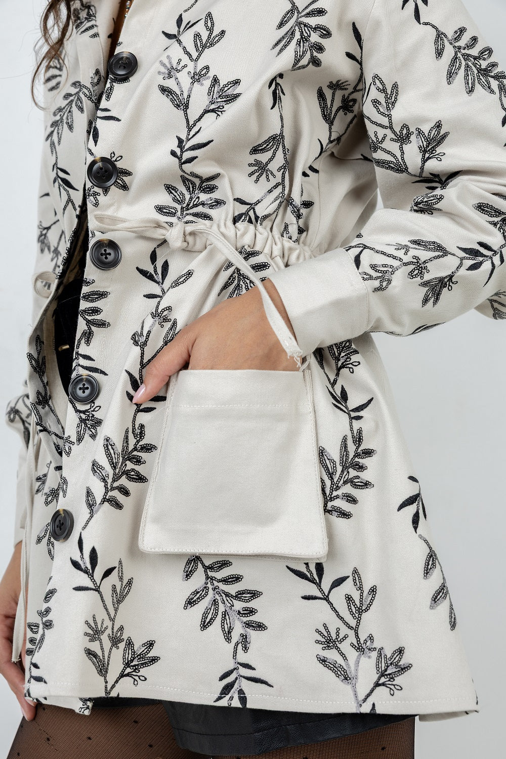 White coat with black floral pattern worn by a person on a white background