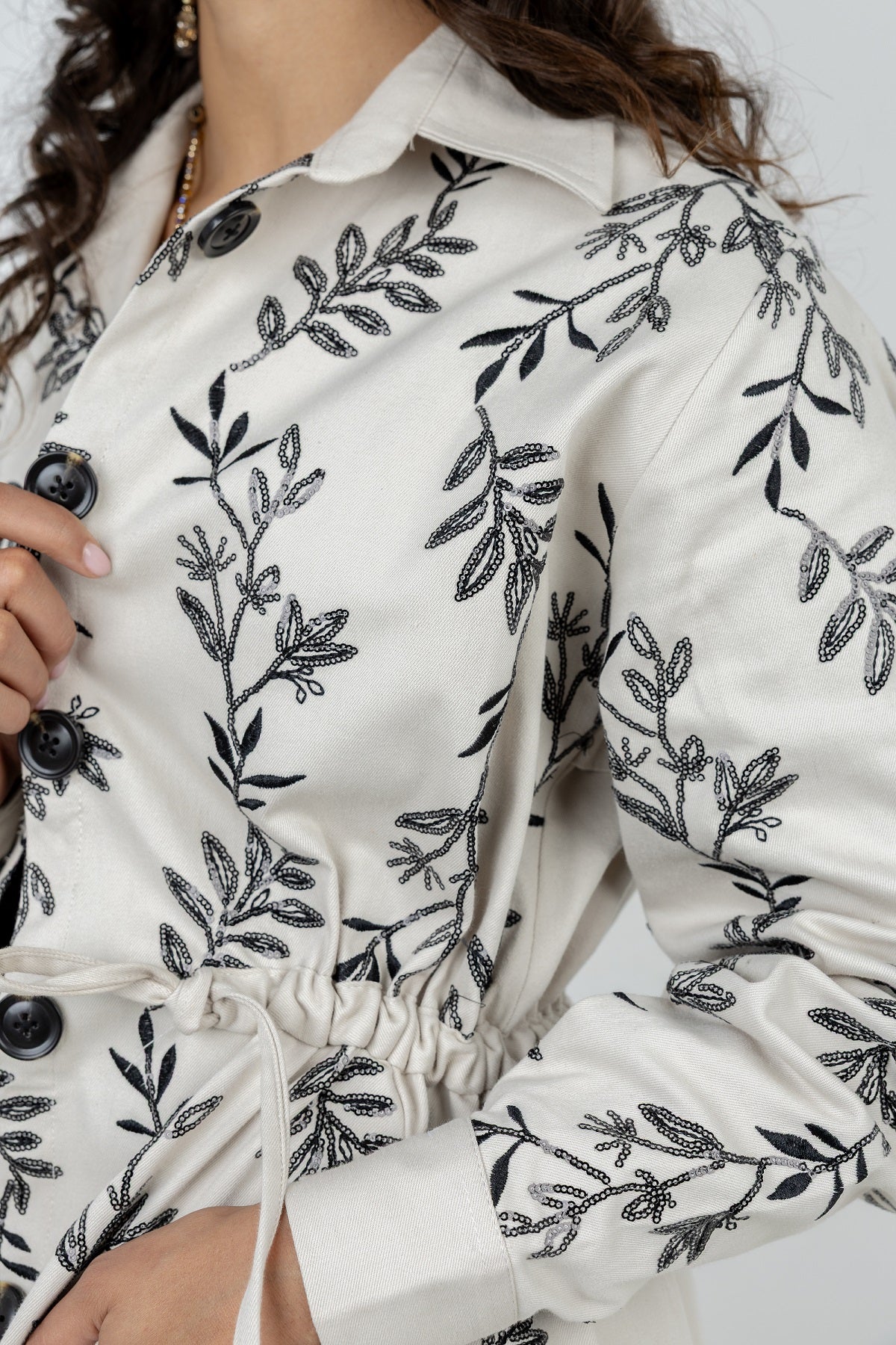 White blouse with black floral embroidery on a white background