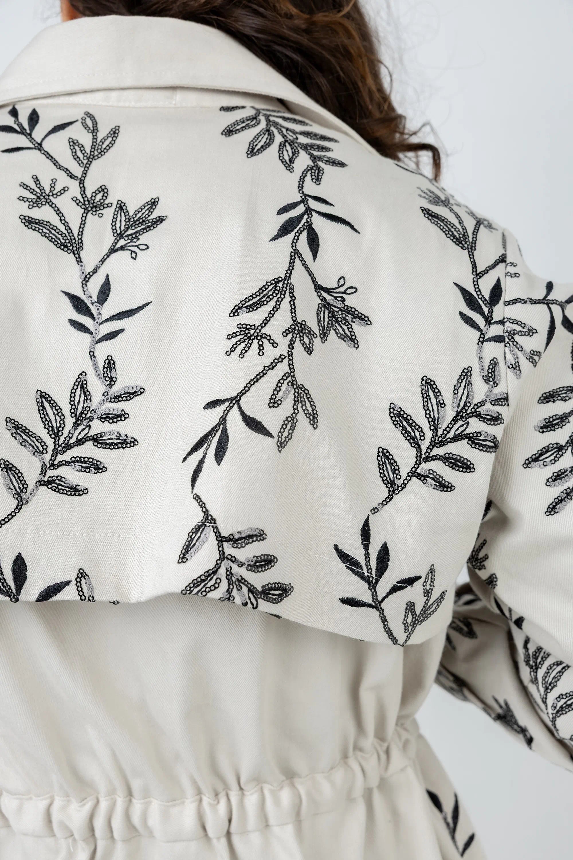 White jacket with black leaf embroidery on a white background