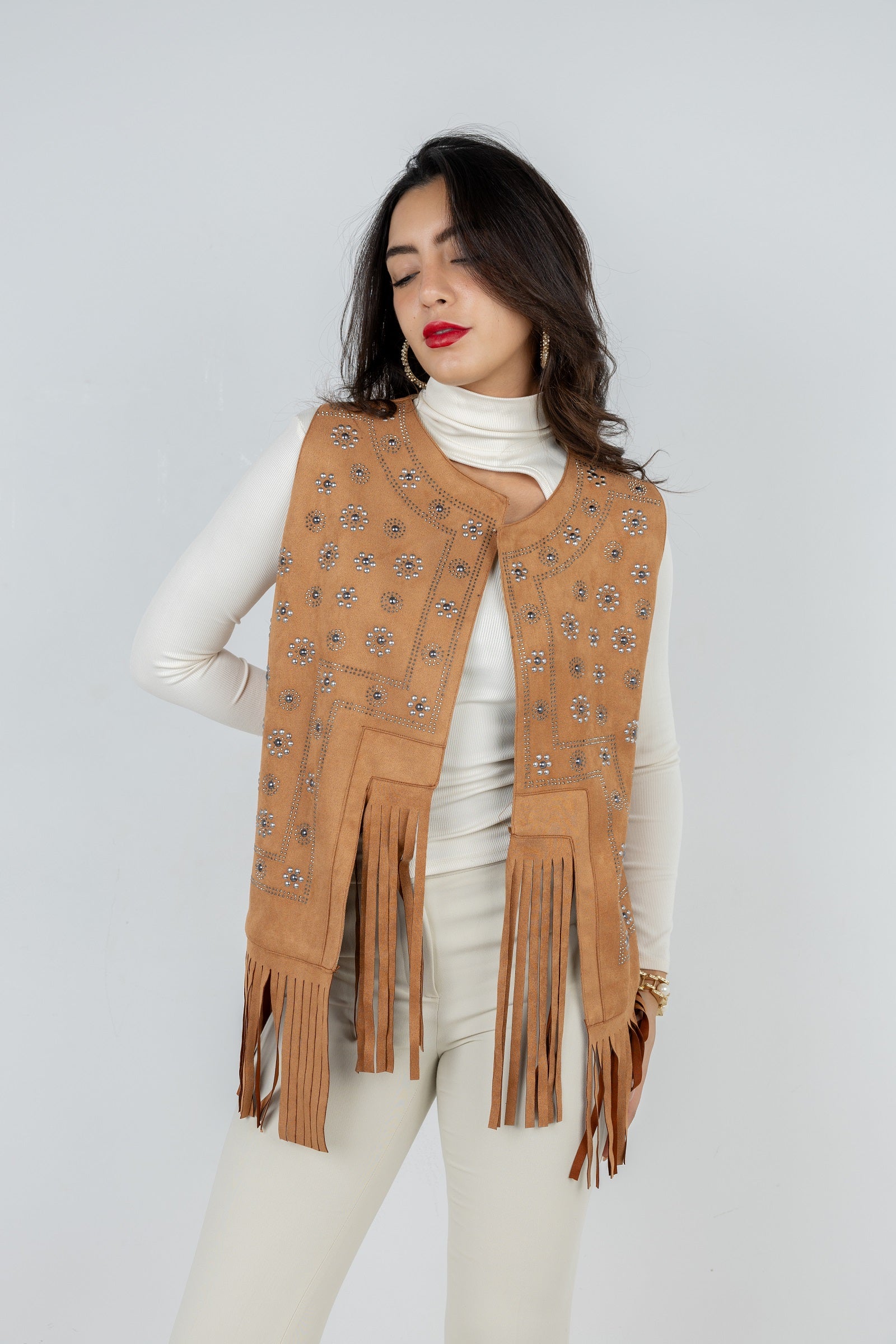 Woman wearing a tan suede vest with fringe details on a white background