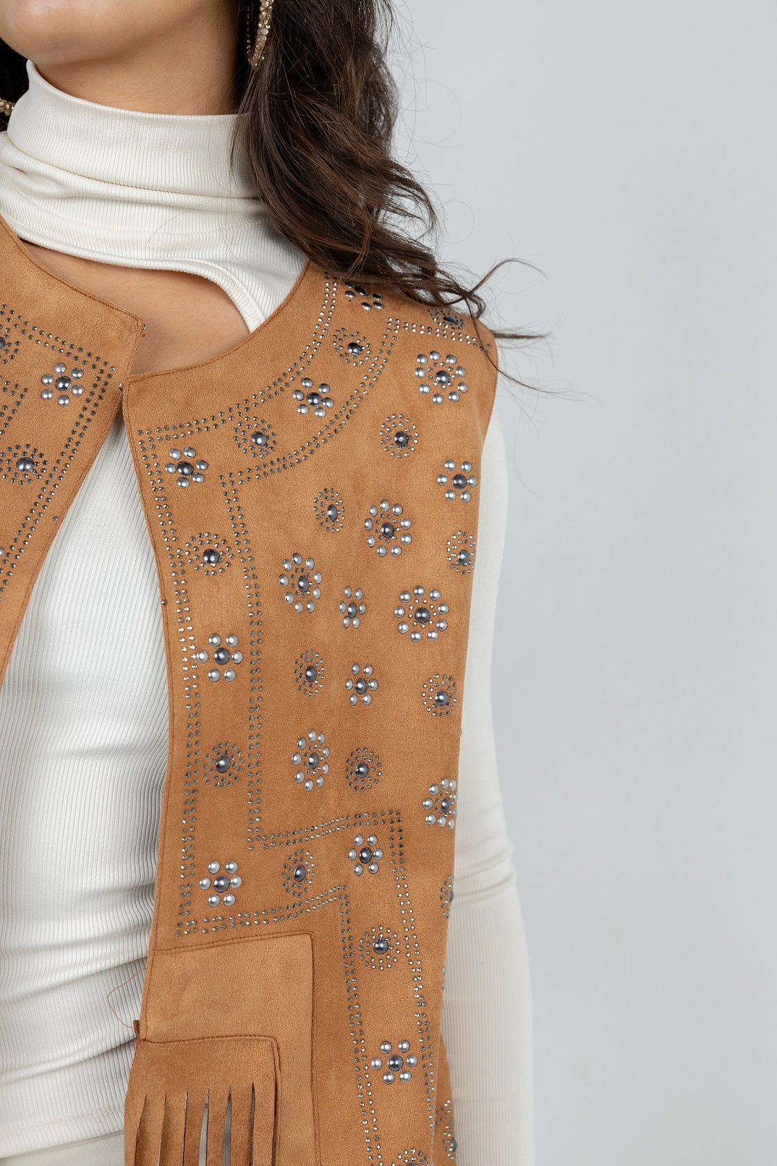Brown embroidered vest over a white outfit on a plain background
