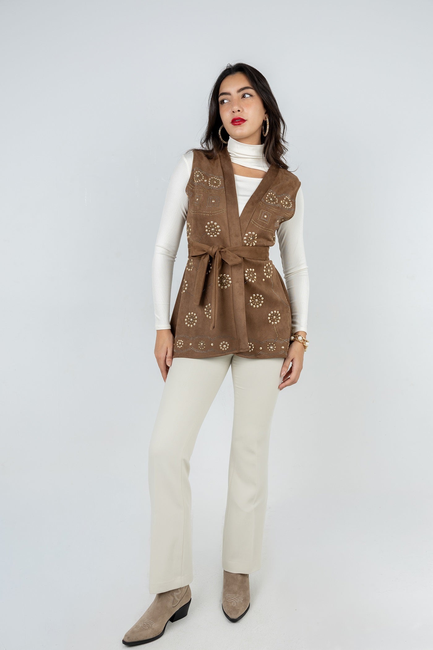 Woman wearing a brown patterned vest over a white top on a white background