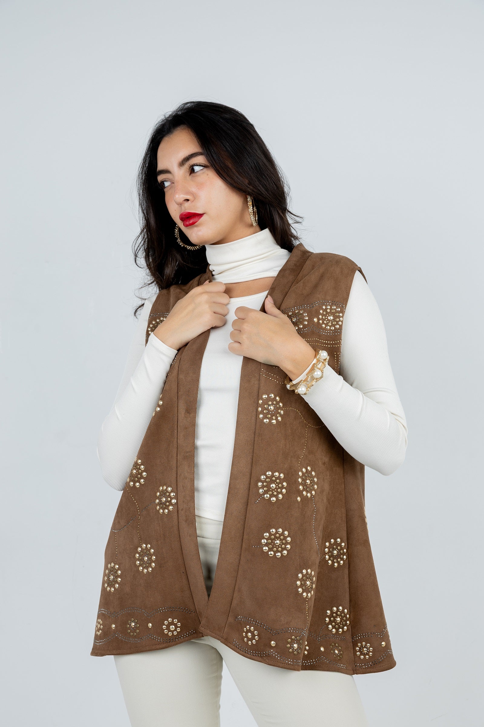 Woman wearing a brown patterned vest over a white top against a light gray background