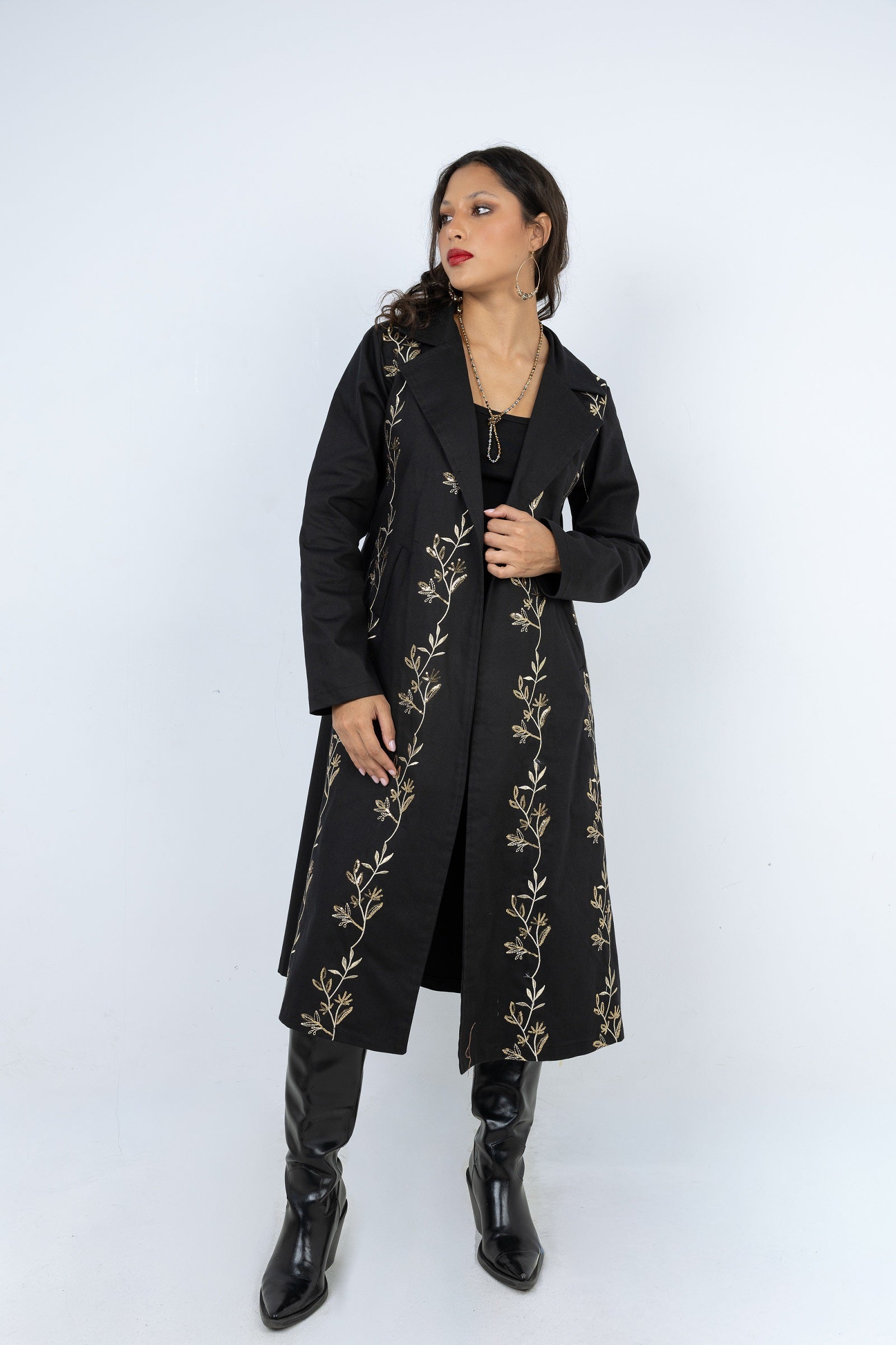 Woman wearing a black coat with gold embroidery on a white background