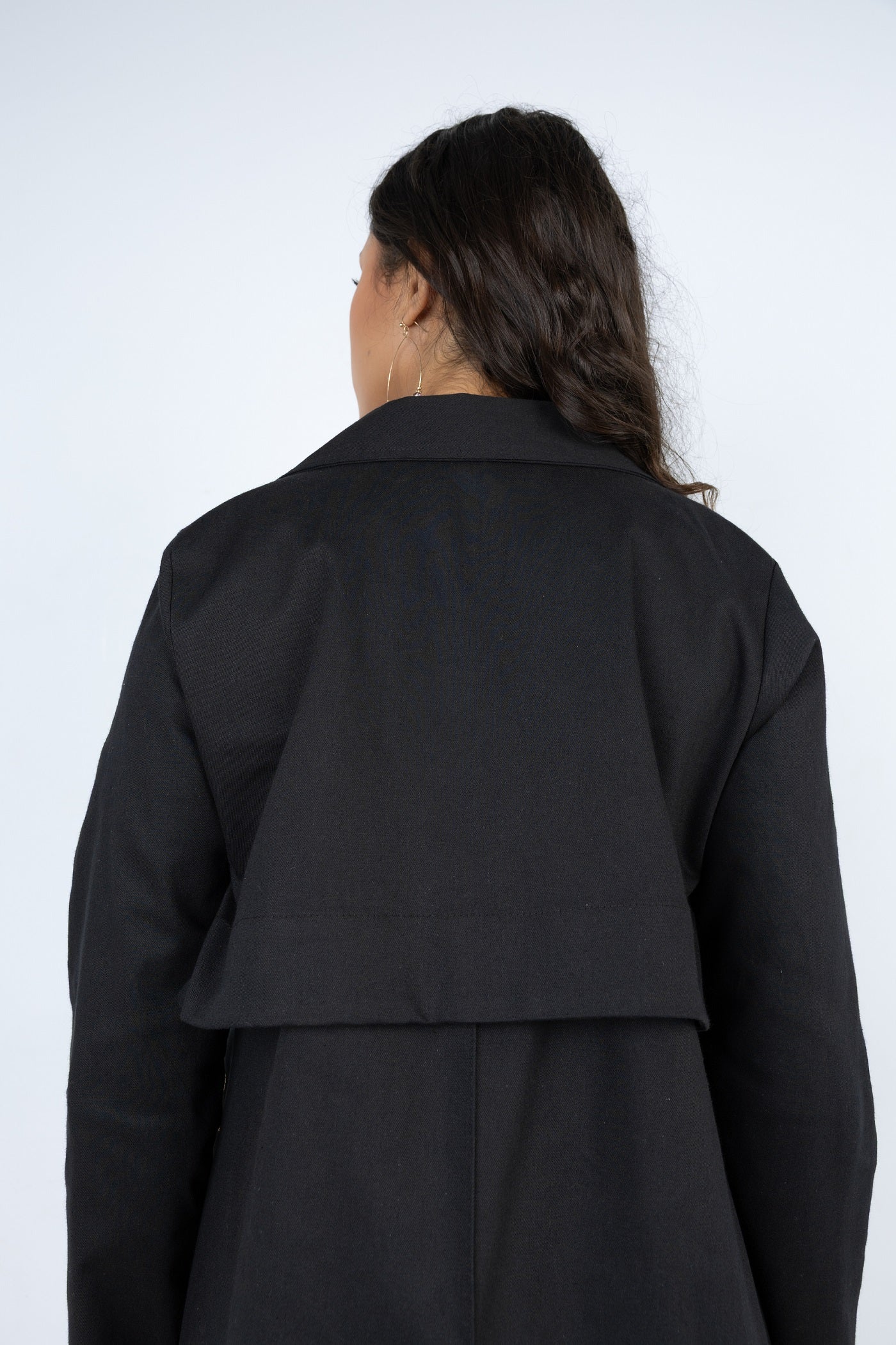 Person wearing a black coat against a white background