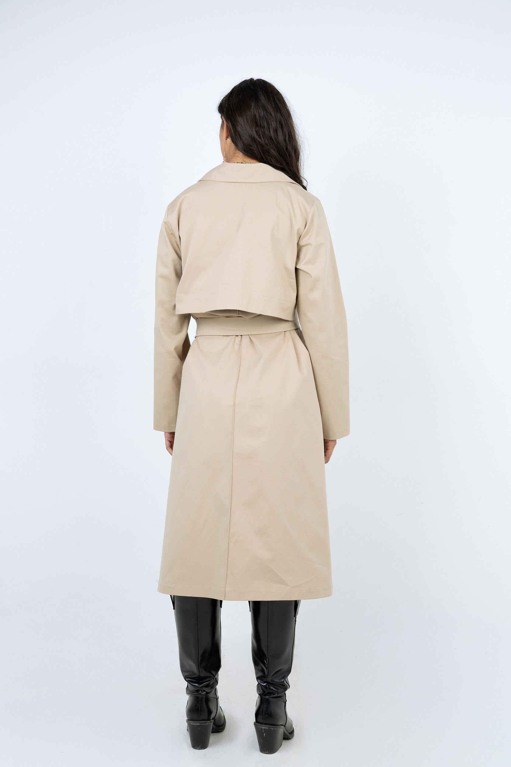 Person wearing a beige trench coat on a white background
