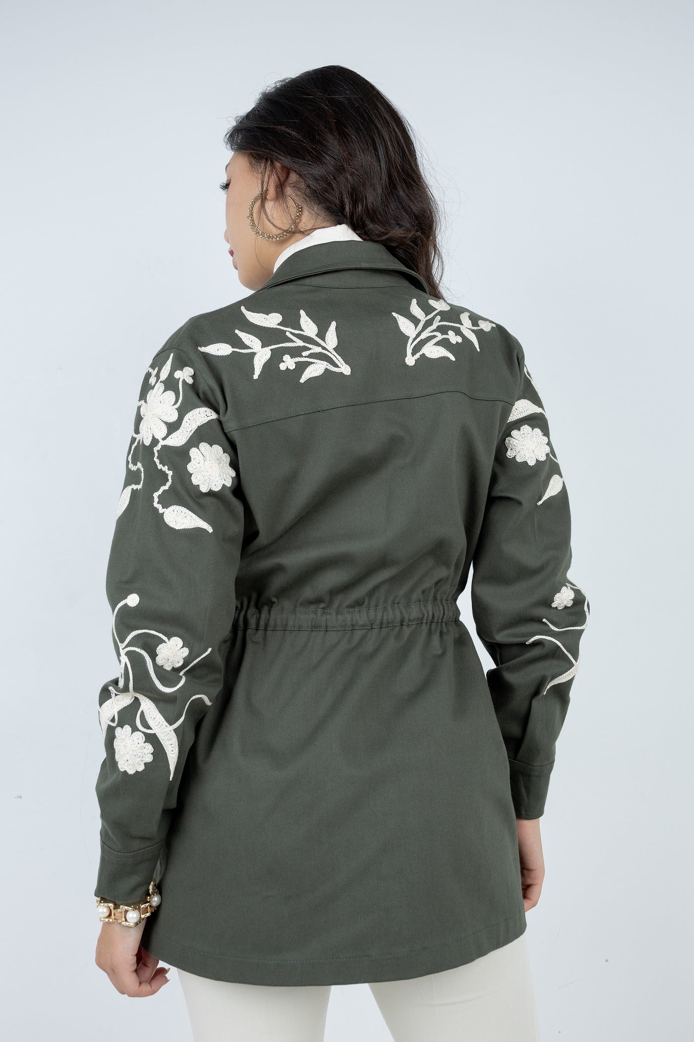 Green jacket with white floral embroidery on a plain background