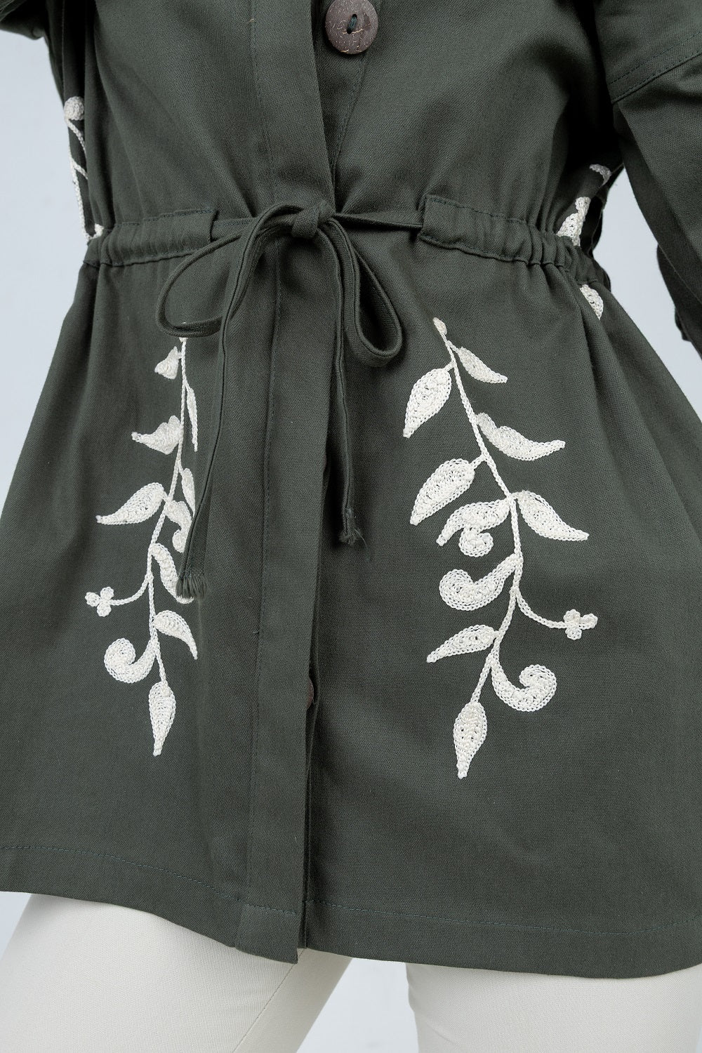 Green dress with white floral patterns on a mannequin against a light gray background